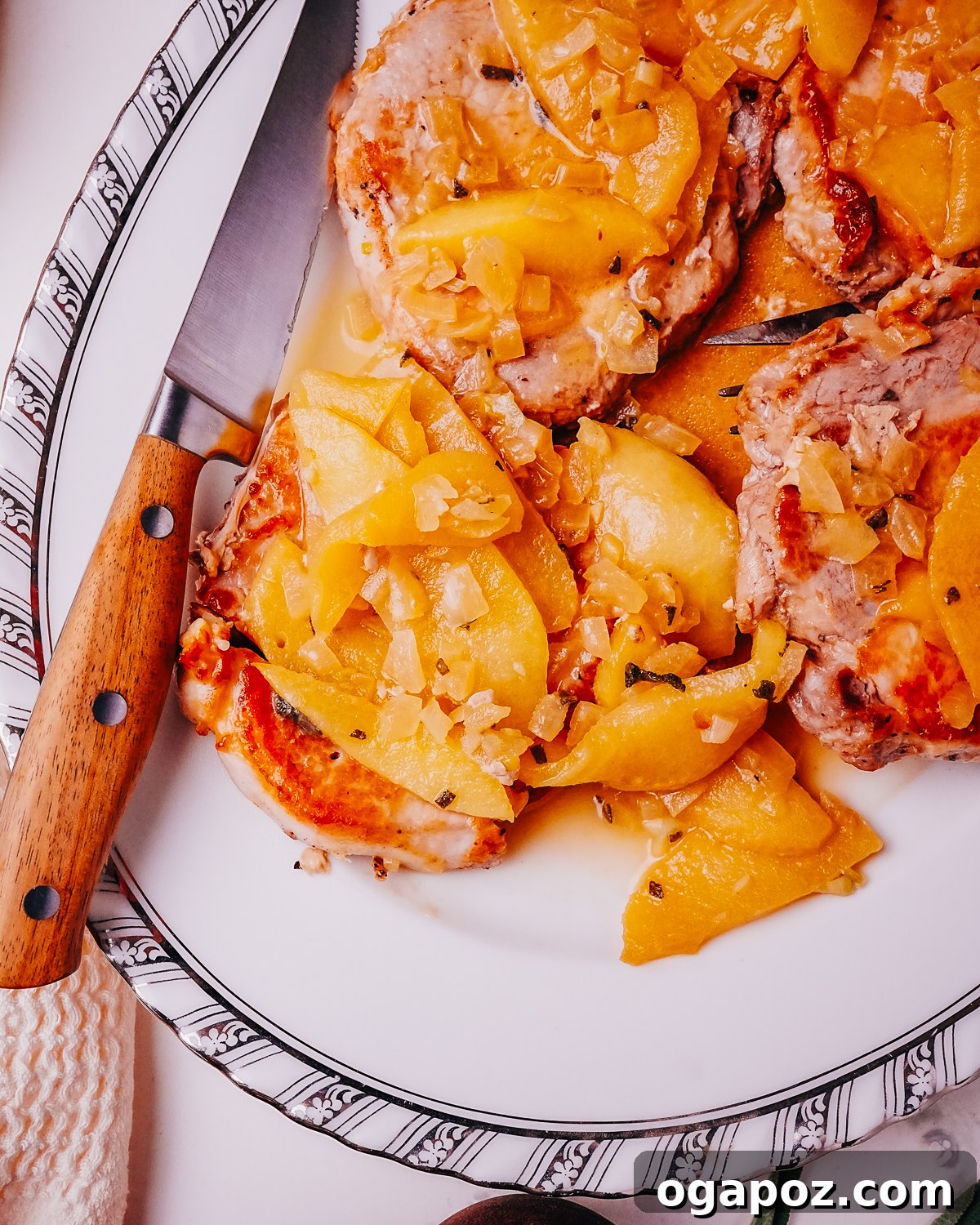Apple Glazed Pork Chops with a Rich Pan Sauce 2 Pork Chops with Apples on a plate with a knife.