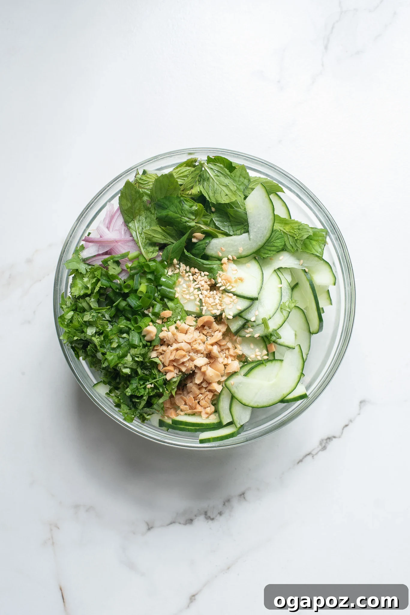 Zesty Thai Cucumber Delight 5 All the salad ingredients, including sliced cucumbers, herbs, and nuts, mixed in a large bowl.