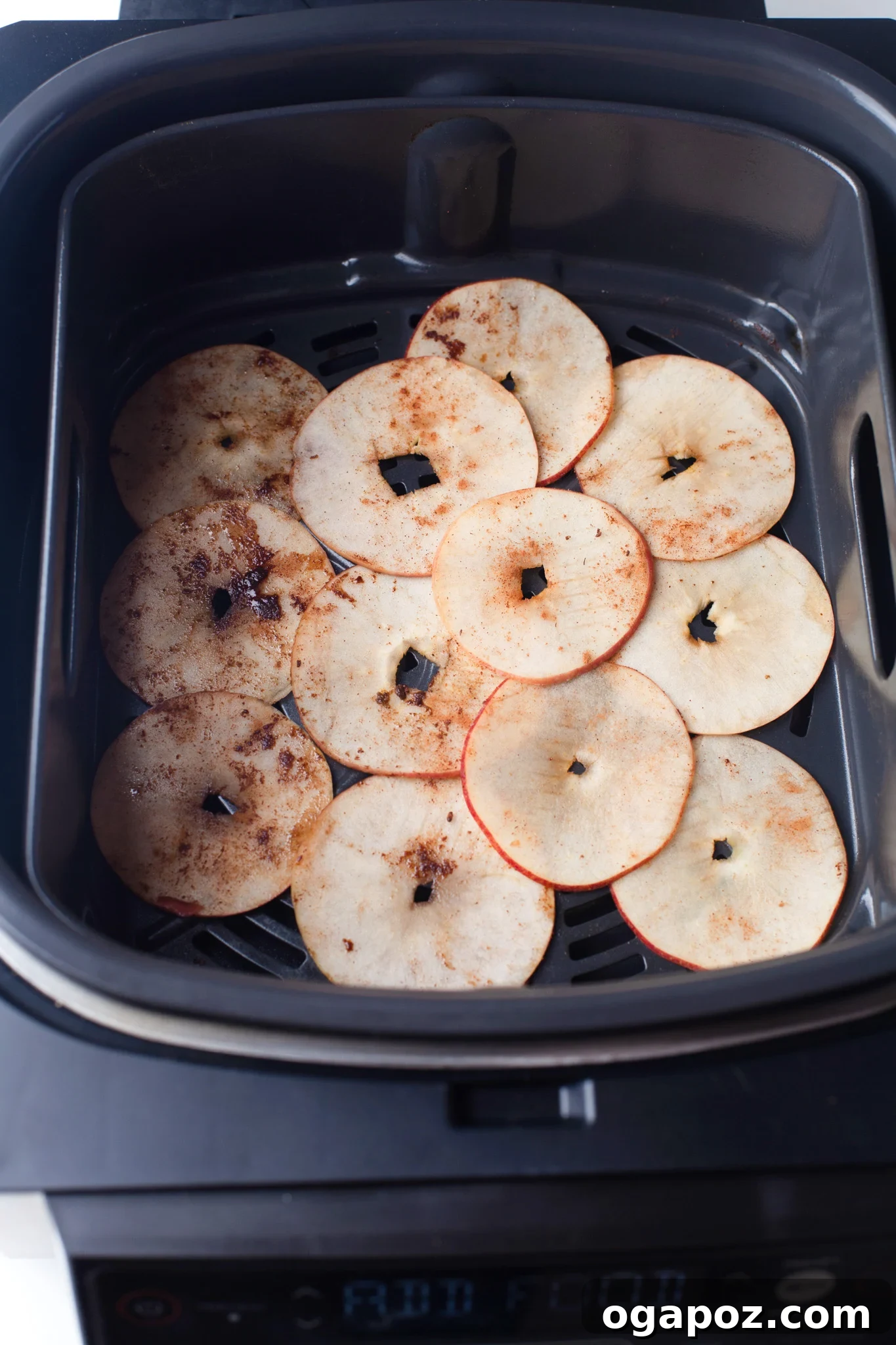Simple Air Fryer Apple Crisps 8 Freshly cooked Air Fryer Apple Chips being carefully removed from the air fryer basket and placed onto a cooling rack.