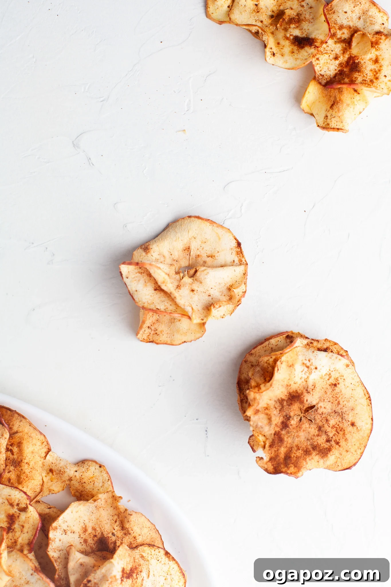 Simple Air Fryer Apple Crisps 10 Freshly prepared Air Fryer Apple Chips thoughtfully spread out on a clean white table, indicating they are ready for careful storage.