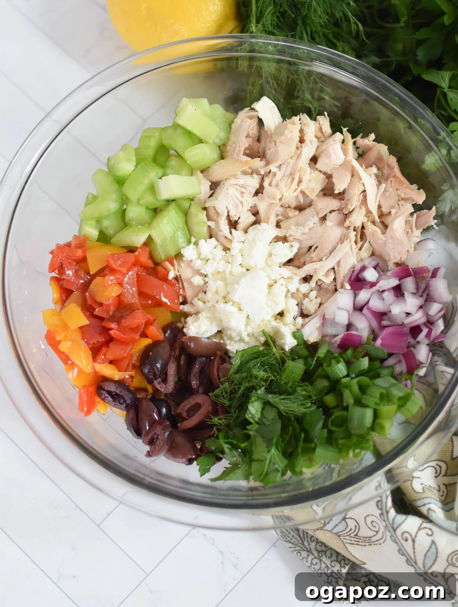 Vibrant Mediterranean Chicken Salad 9 Healthy Mediterranean Chicken Salad ingredients mixed together in a large glass bowl, ready to be served.