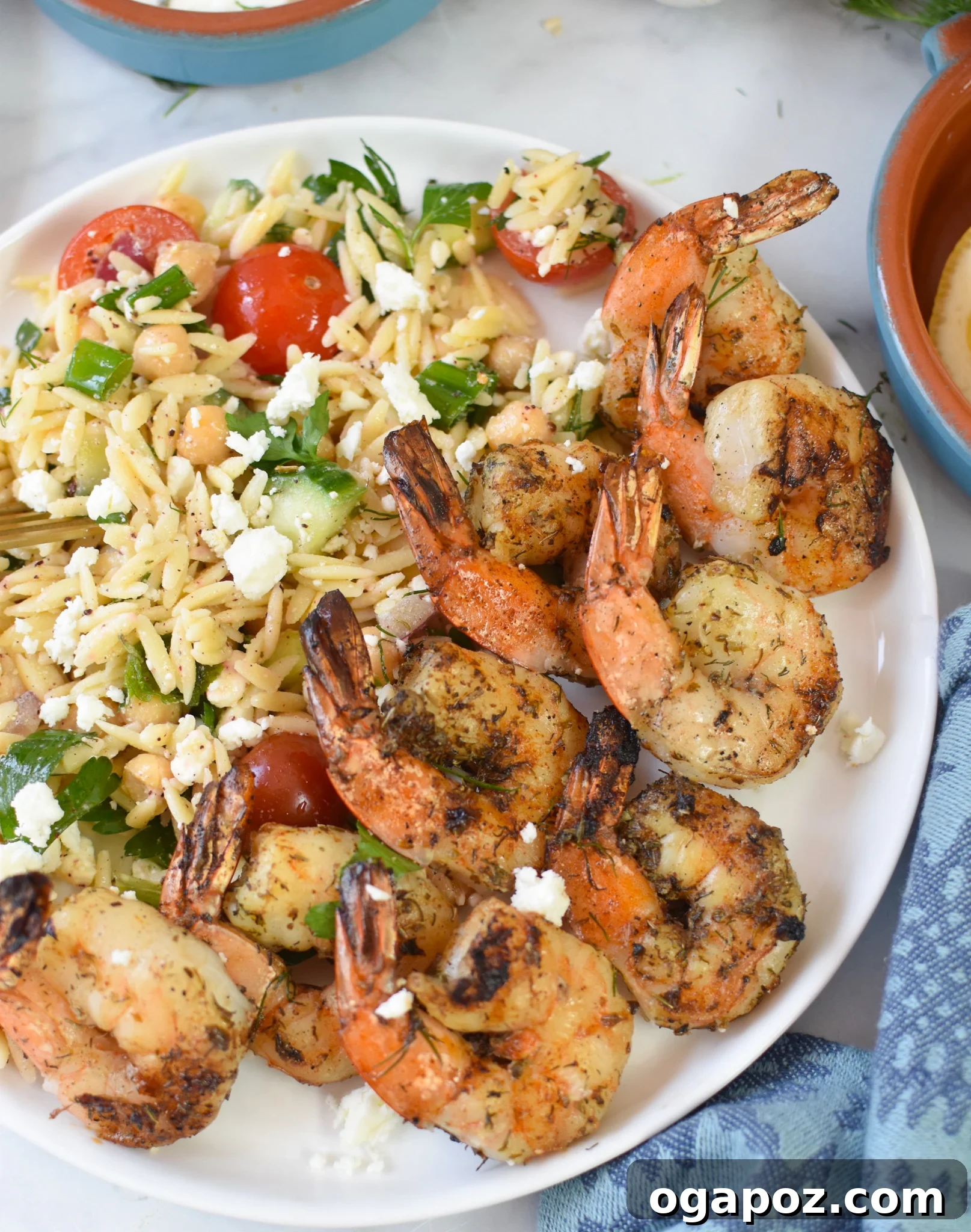 Zesty Greek Shrimp Marinade 3 Grilled Greek shrimp arranged beautifully on a plate with a side of refreshing orzo salad, indicating a perfect meal pairing.