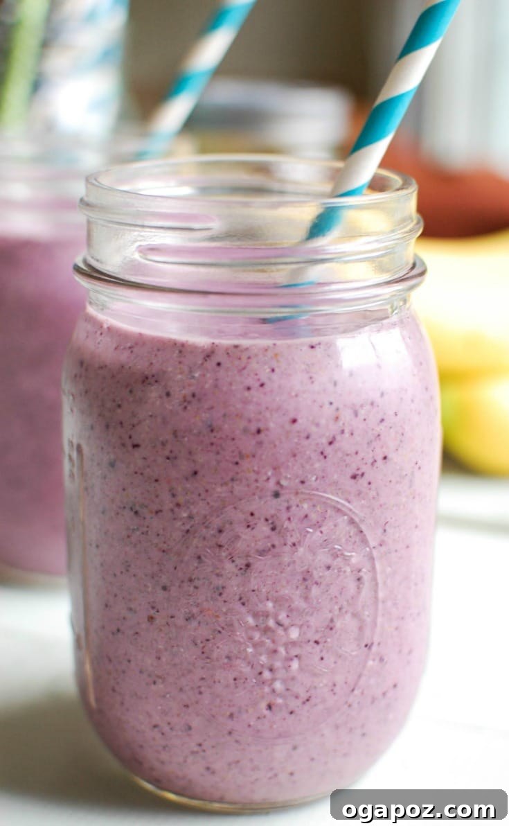 Velvet Blueberry Banana Smoothie 4 A refreshing Blueberry Banana Smoothie served in a clear glass with a blue straw, inviting a healthy sip.