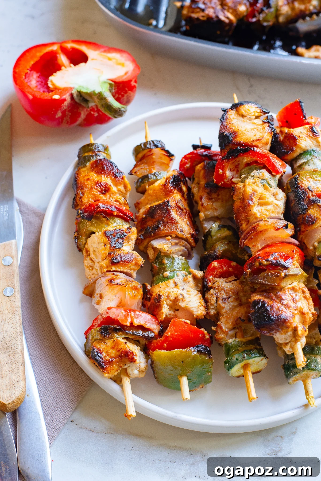 Zesty Greek Lemon Chicken Skewers 2 Delicious Greek Marinated Chicken Kabobs with Lemon served on a white plate, garnished with fresh herbs.