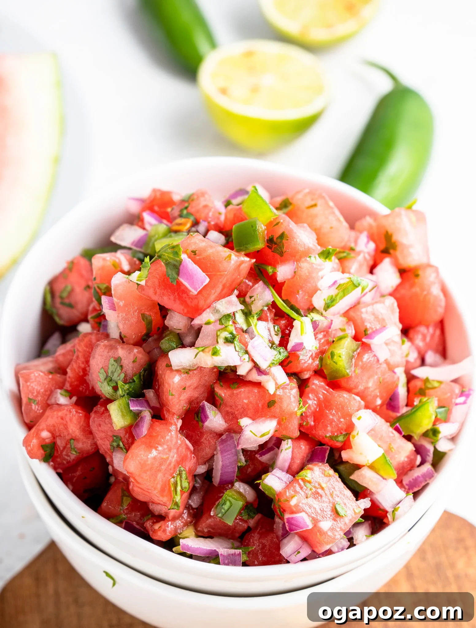Summer Watermelon Salsa 3 Easy Watermelon Salsa in a white bowl with fresh jalapeños and cilantro leaves scattered around.