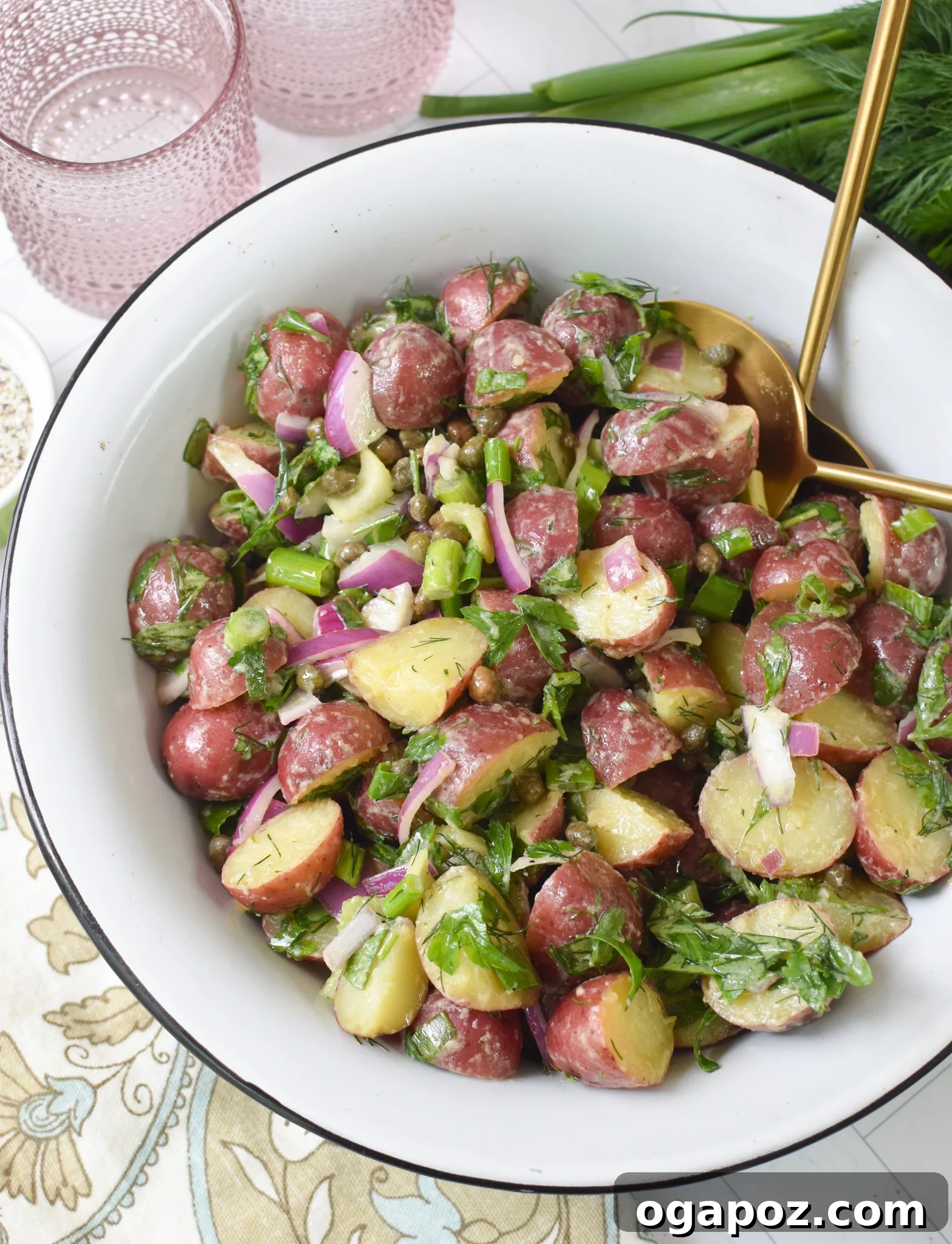 Bright and Tangy Potato Salad 2 No Mayo Potato Salad in a white bowl with gold spoons, highlighting its fresh ingredients.