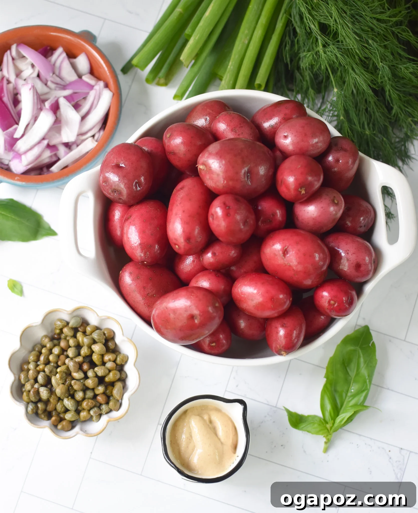 Bright and Tangy Potato Salad 6 All ingredients for No Mayo Potato Salad laid out on a table, including fresh herbs, potatoes, and dressing components.