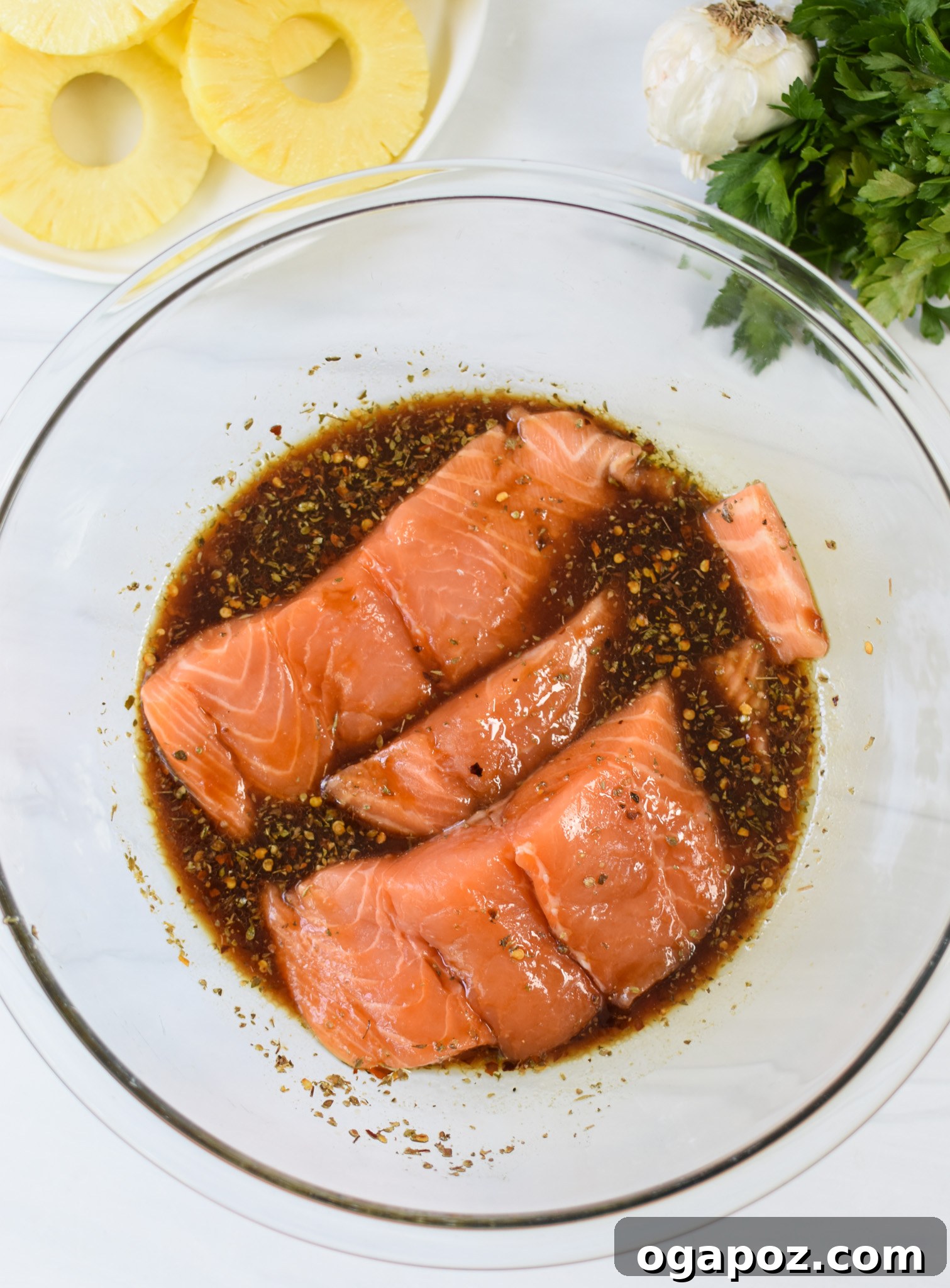 Aloha Grilled Salmon 9 Salmon fillets soaking in the Hawaiian marinade in a bowl with fresh pineapple slices.
