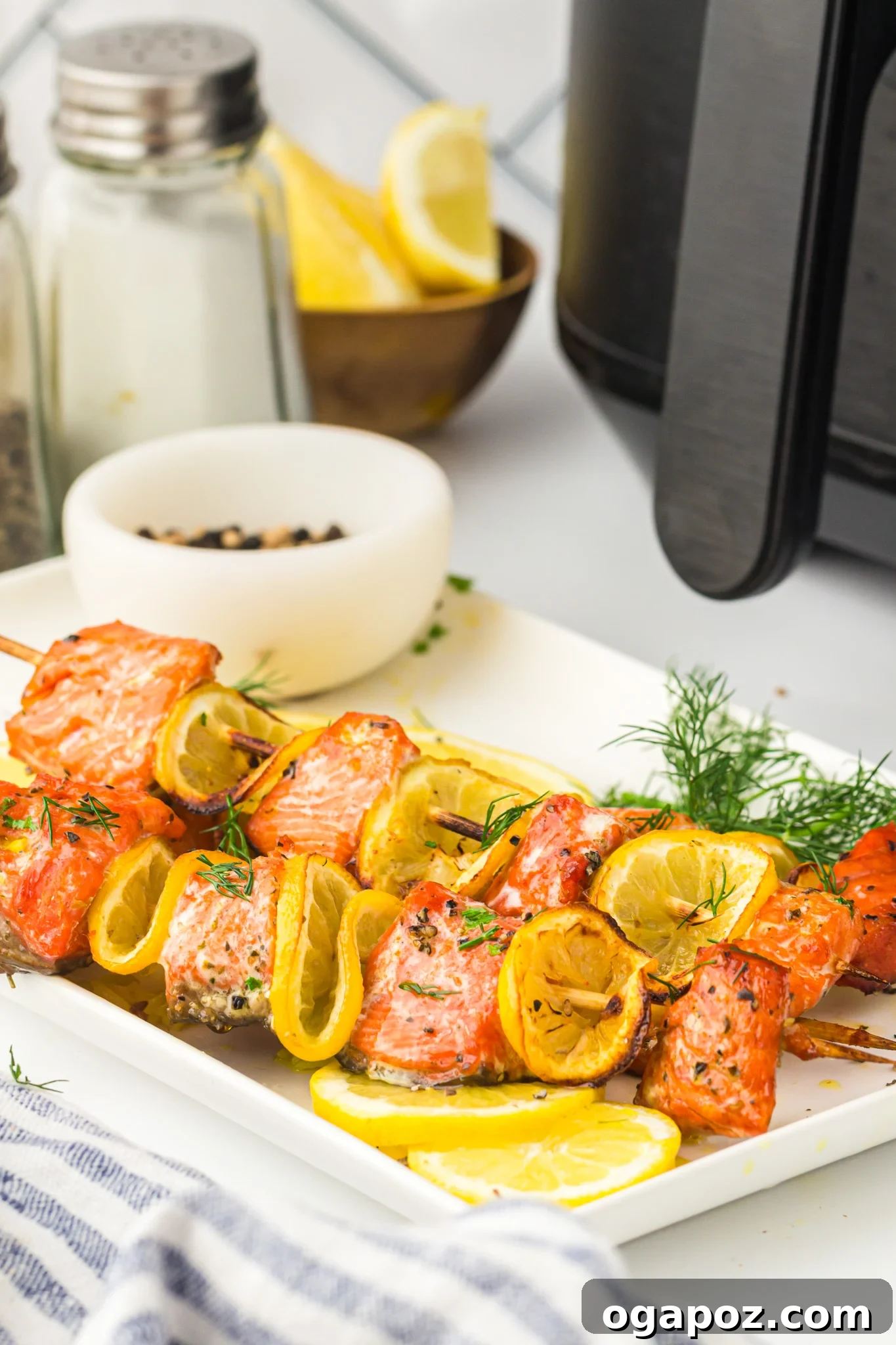 Quick Zesty Salmon Skewers 7 Cooked Easy Lemon Salmon Kabobs on a white plate, with an air fryer blurred in the background, highlighting the cooking method.