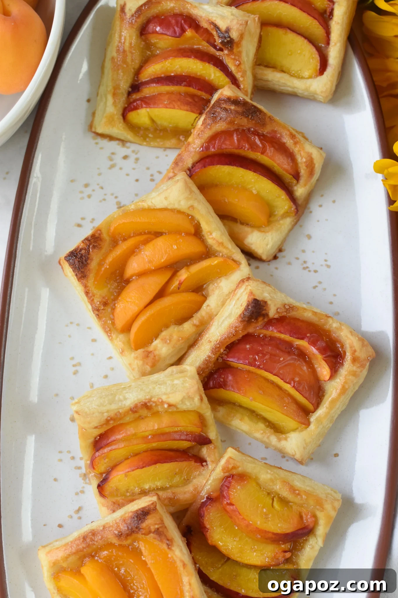 Effortless Golden Peach Tart 11 A close-up of an individual Easy Peach Tart, sparkling with turbinado sugar on its golden, flaky crust, emphasizing its texture and delicious appeal.