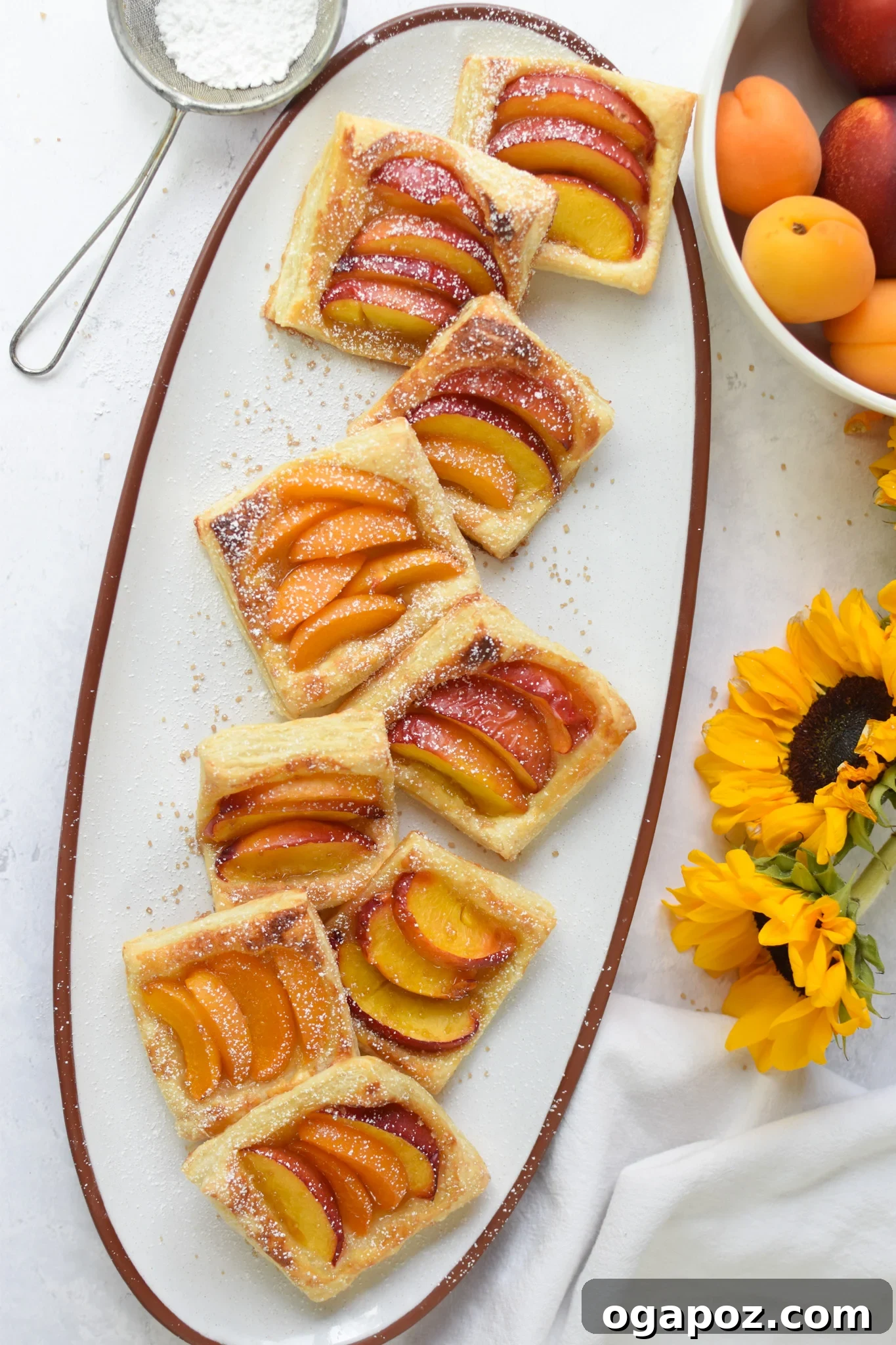 Effortless Golden Peach Tart 4 A selection of baked Easy Peach Tarts presented beautifully on a white platter, highlighting their golden crusts and colorful fruit toppings.