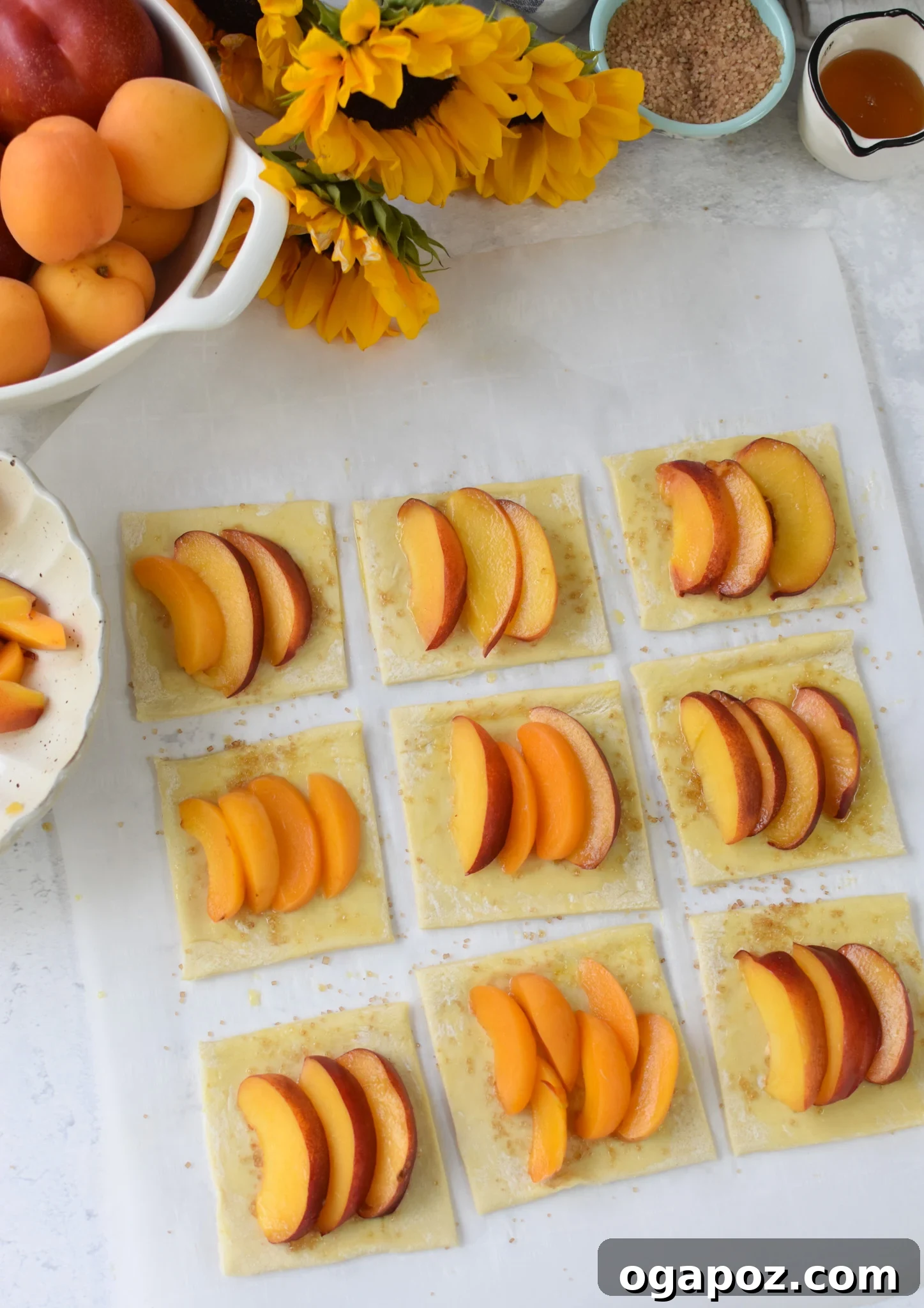 Effortless Golden Peach Tart 9 Unbaked peach tarts, with fruit, sugar, and honey meticulously arranged on puff pastry squares on a baking sheet, poised for the oven.