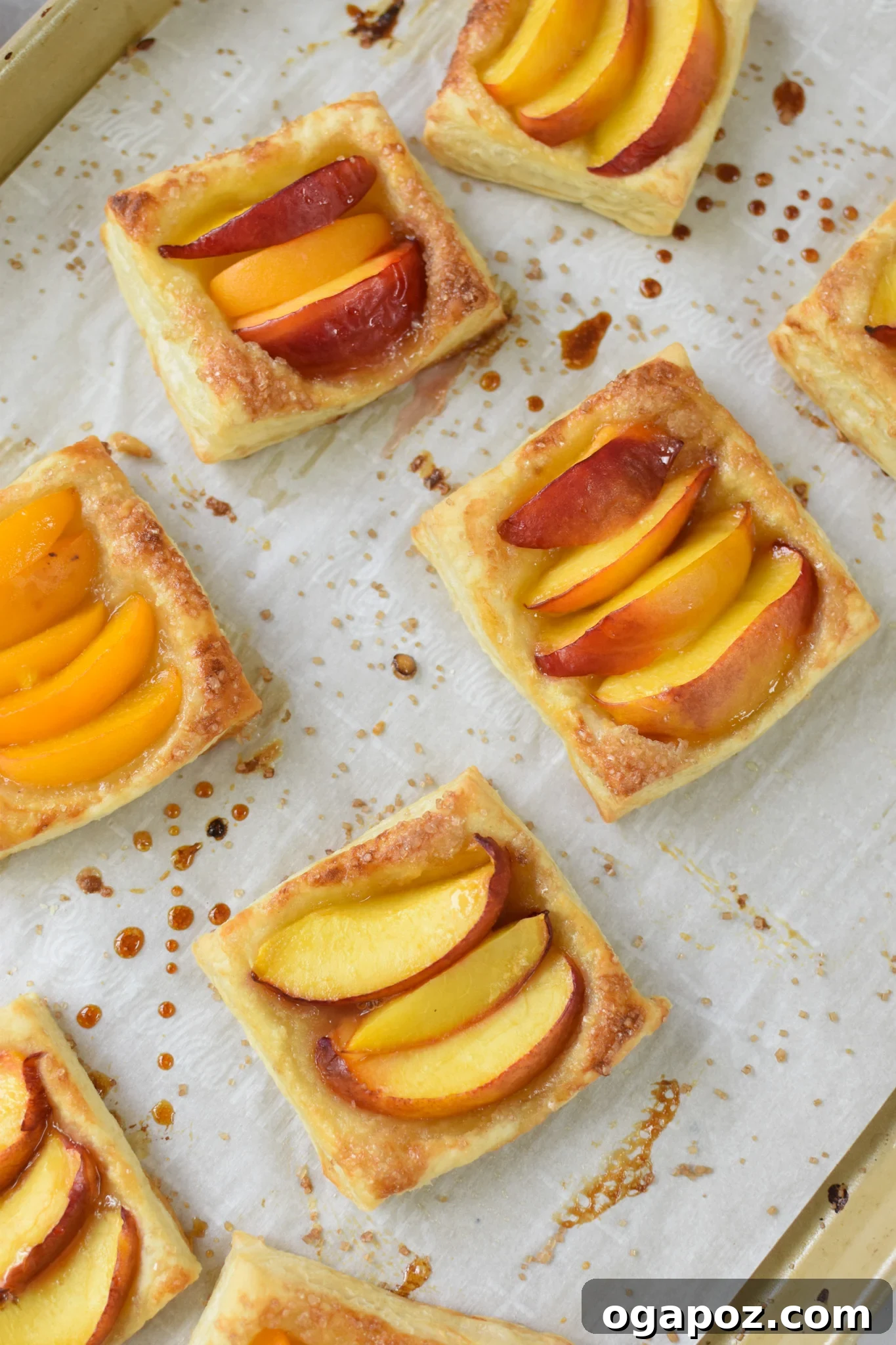 Effortless Golden Peach Tart 10 Freshly baked Easy Peach Tarts on a baking sheet, showcasing their perfectly golden, puffy crusts and tender fruit. Ready to be enjoyed.