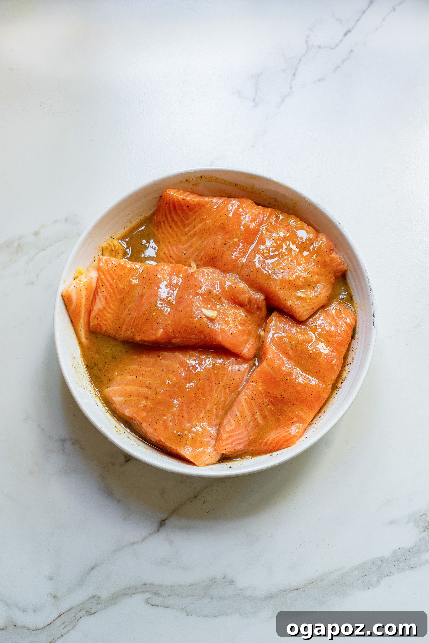 Salmon fillets soaking in the honey mustard marinade in a baking dish, ready for grilling.
