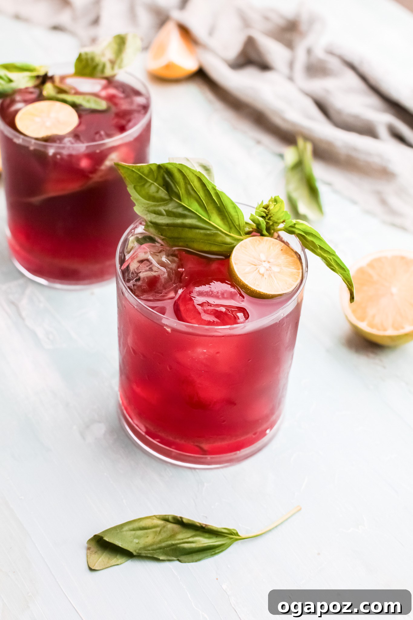 Spiked Cherry Lime Delight 2 A chilled glass of Vodka Cherry Limeade garnished with fresh basil and lime slices, ideal for summer.