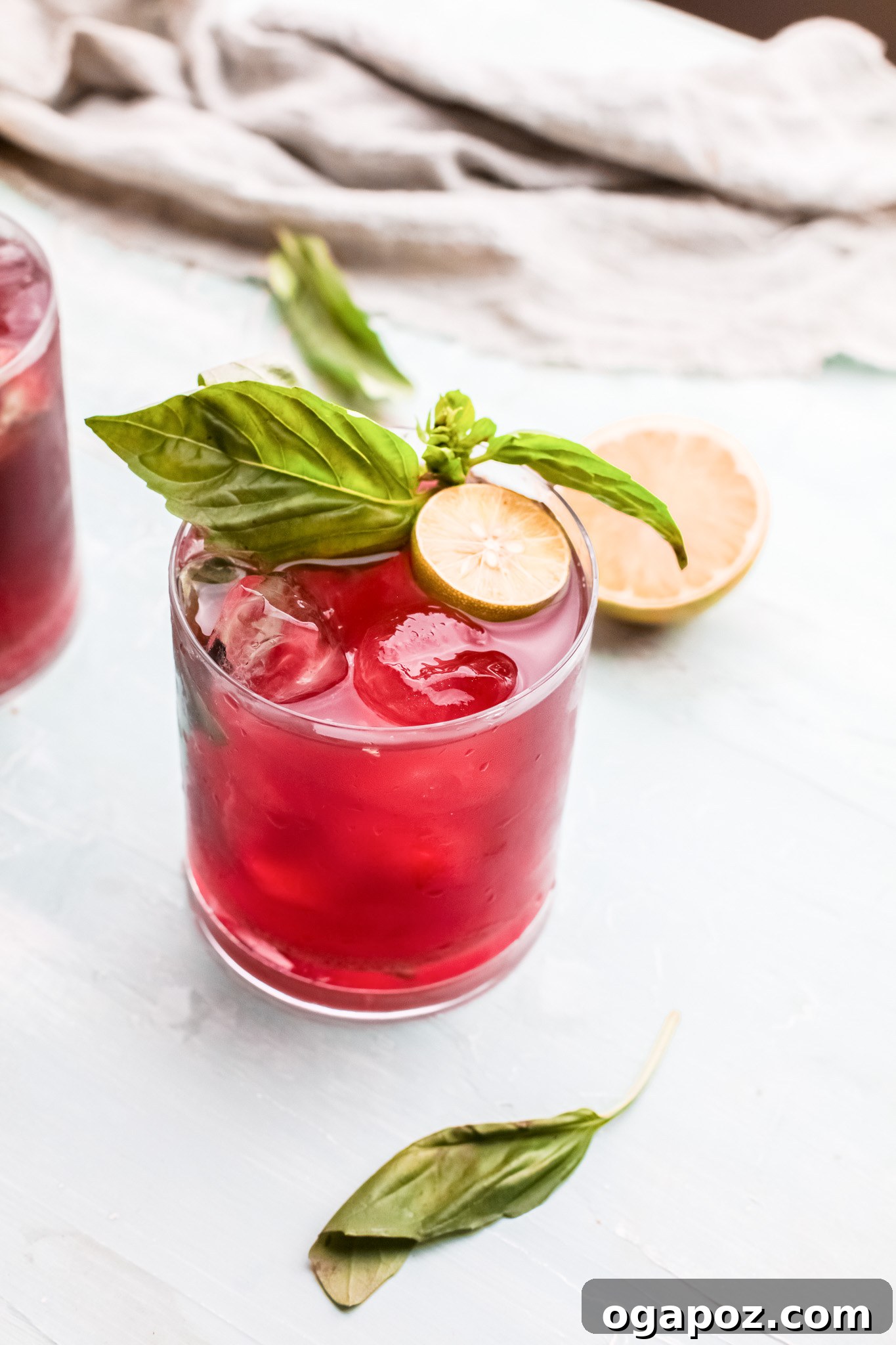 Spiked Cherry Lime Delight 5 A glass of Vodka Cherry Limeade with lime and basil garnish, showcasing the drink's appealing color.