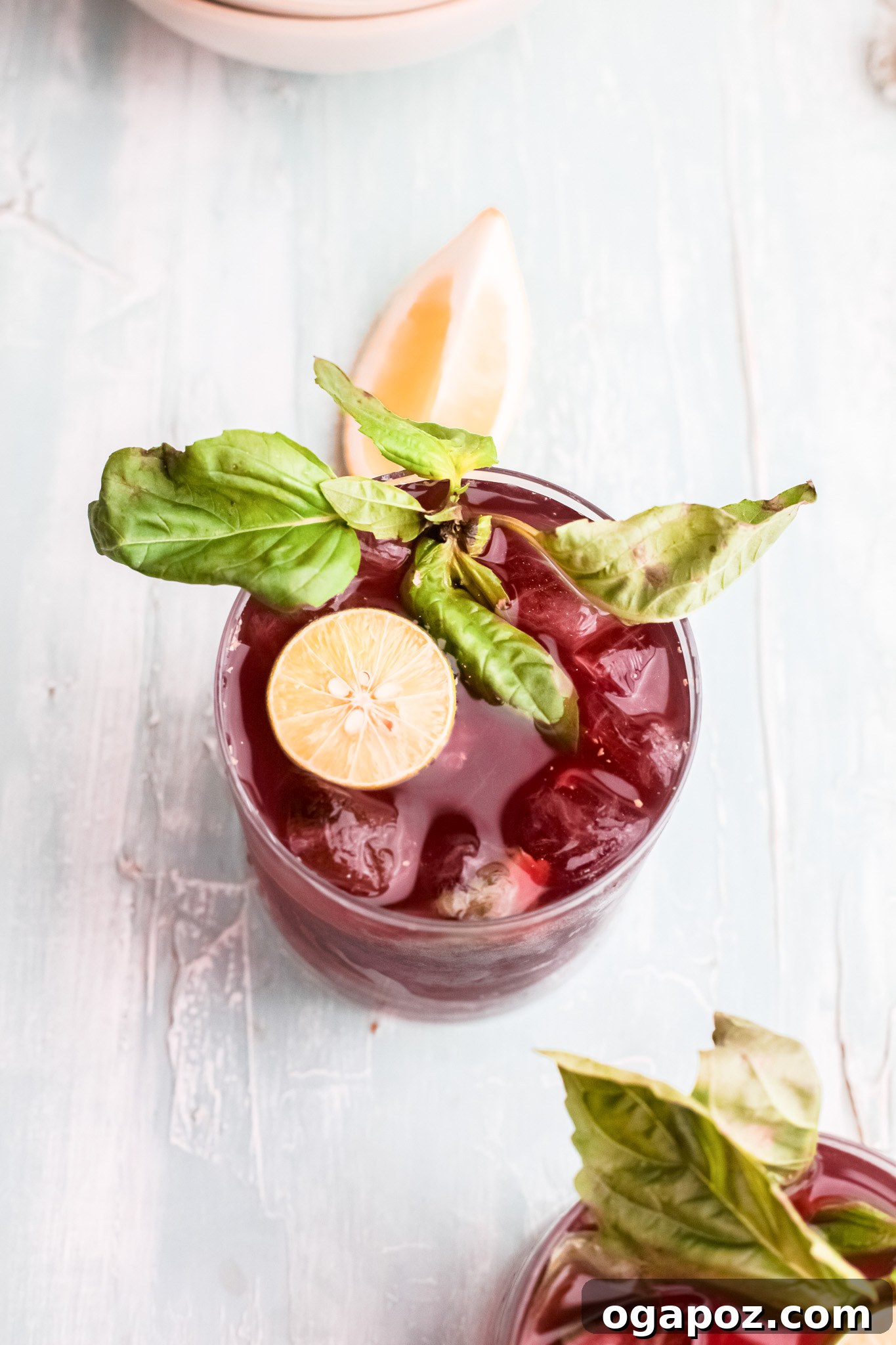 Spiked Cherry Lime Delight 9 A vibrant Vodka Cherry Limeade cocktail in a clear glass, garnished with a lime slice and fresh basil, ready for a warm day.