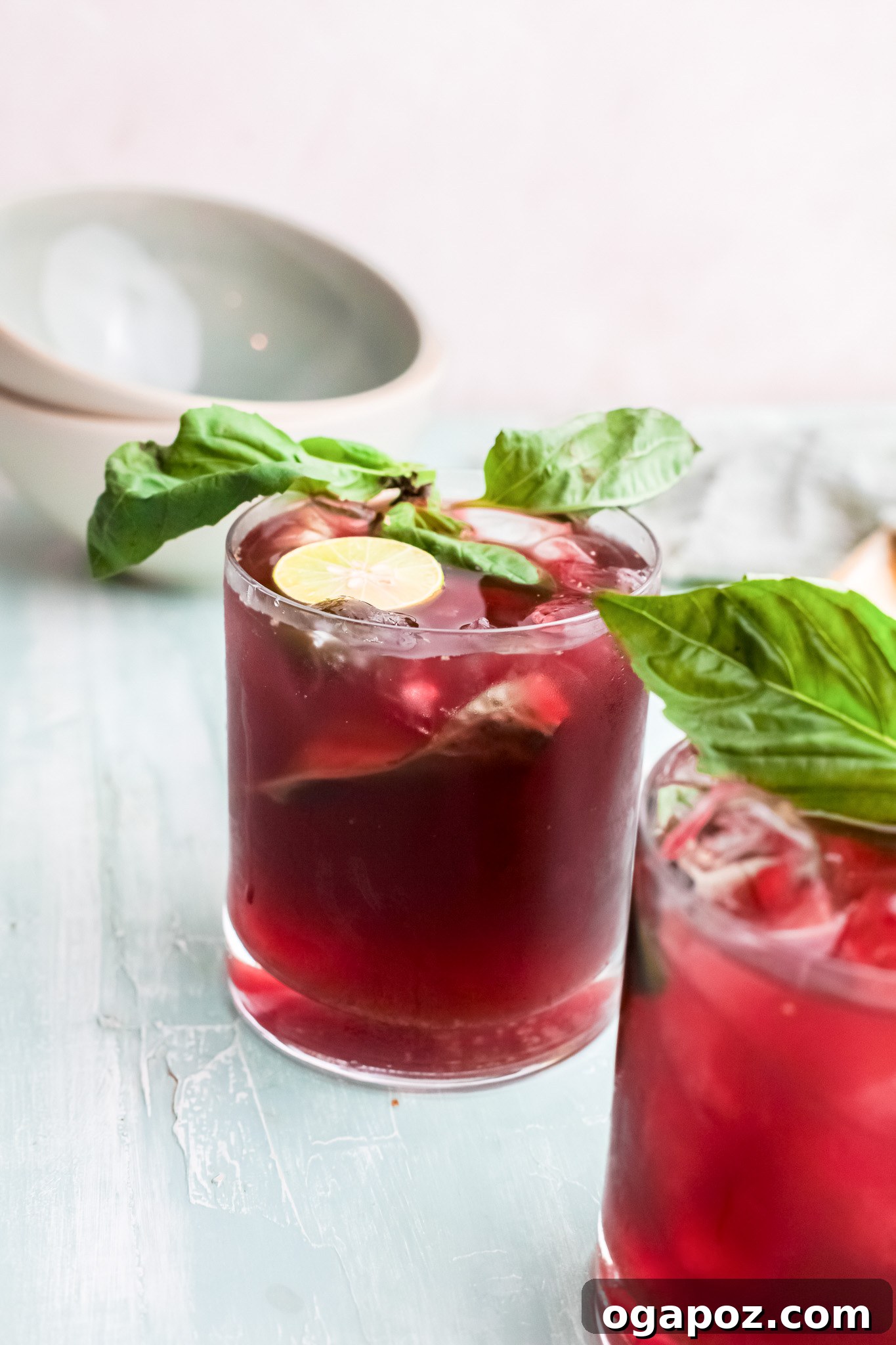 Spiked Cherry Lime Delight 10 A single glass of Vodka Cherry Limeade with lime and basil, glistening in the light.