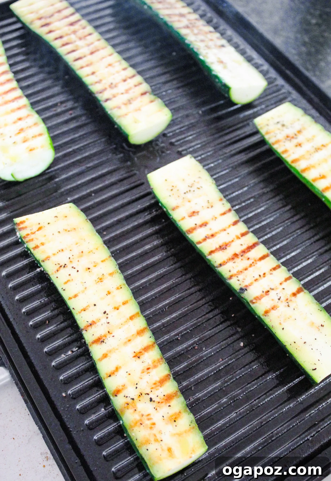 Effortless Zucchini Tacos 5 Zucchini halves grilling on a hot barbecue, showing char marks.