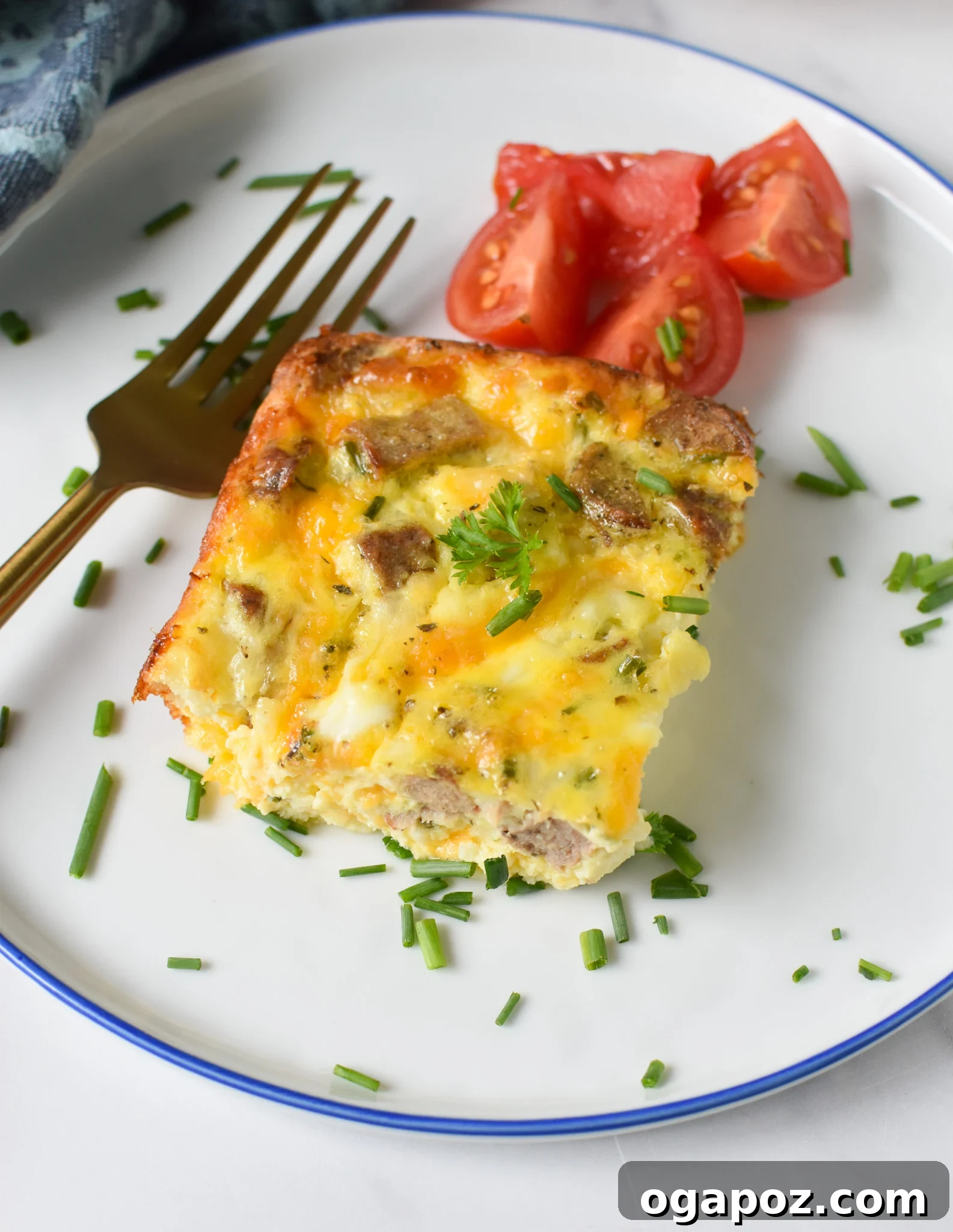 Savory Cottage Cheese Egg Bake 4 A perfectly portioned slice of Cottage Cheese Baked Eggs on a white plate, elegantly garnished with fresh herbs and a halved cherry tomato, ready to be enjoyed.