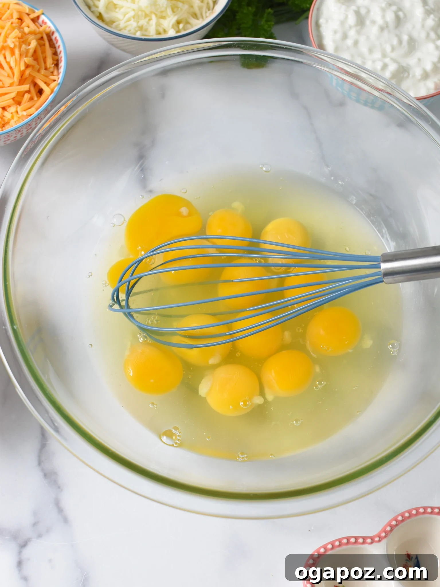 Savory Cottage Cheese Egg Bake 5 A close-up of eggs being cracked and vigorously whisked in a large bowl, demonstrating the first step in preparing Cottage Cheese Baked Eggs.