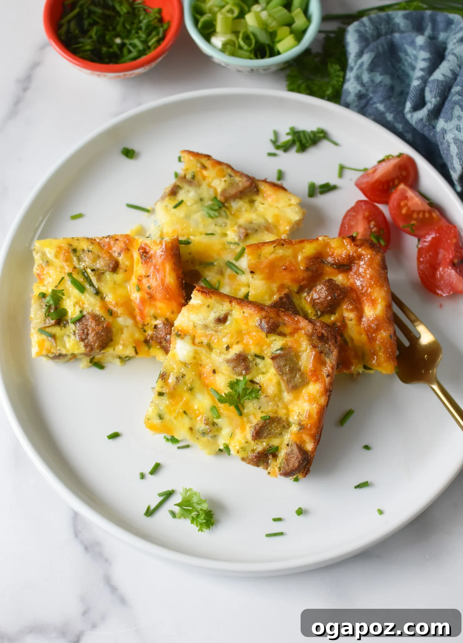 Savory Cottage Cheese Egg Bake 10 Two neatly cut squares of Cottage Cheese Baked Eggs presented on a white plate, adorned with fresh herbs and a vibrant cherry tomato, invitingly ready to be consumed.