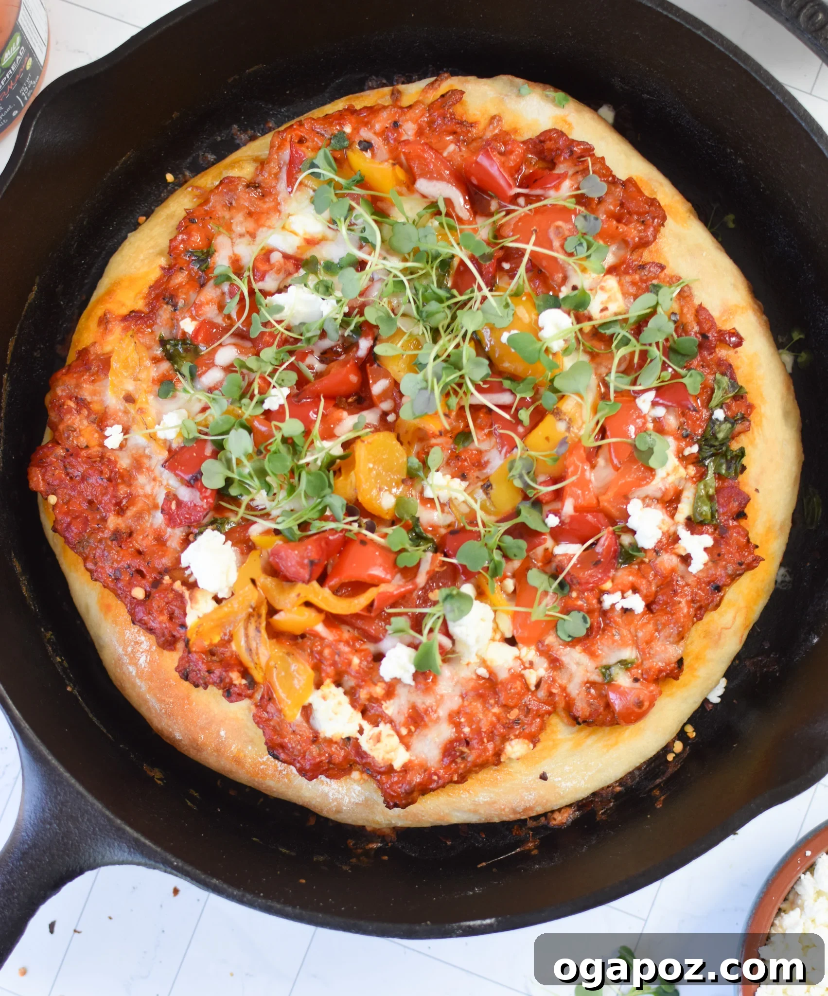 Sun-Kissed Mediterranean Skillet Pizza 3 Cast Iron Mediterranean Pizza fresh out of the skillet, still in the pan, highlighting its crispy crust and bubbly cheese.
