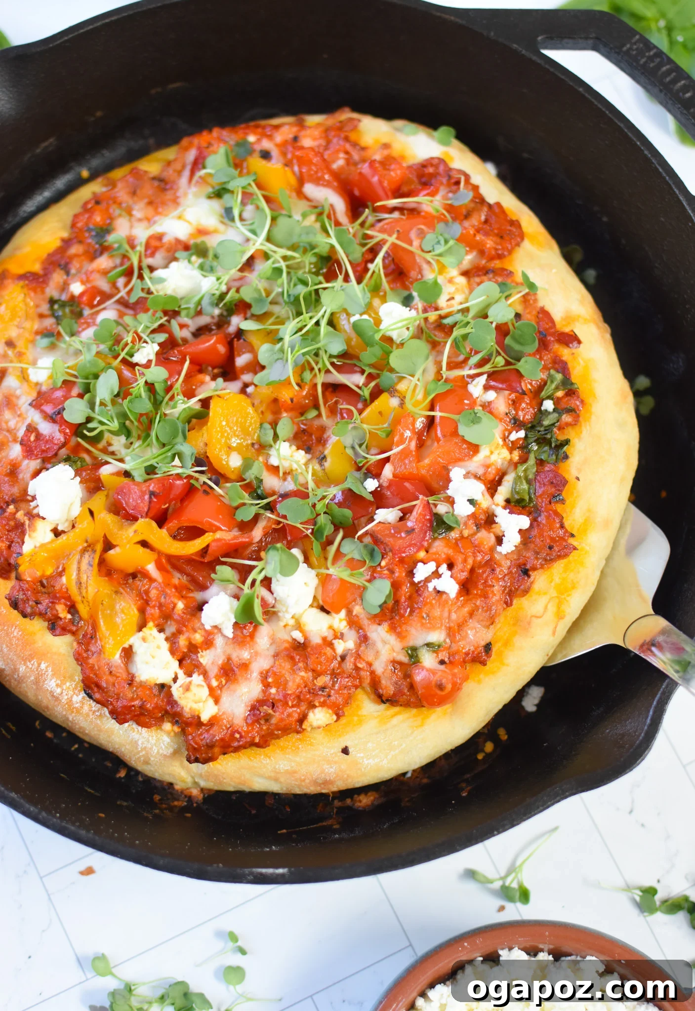 Sun-Kissed Mediterranean Skillet Pizza 10 Cast Iron Mediterranean Pizza in a skillet with a spatula, indicating it's ready to be served.