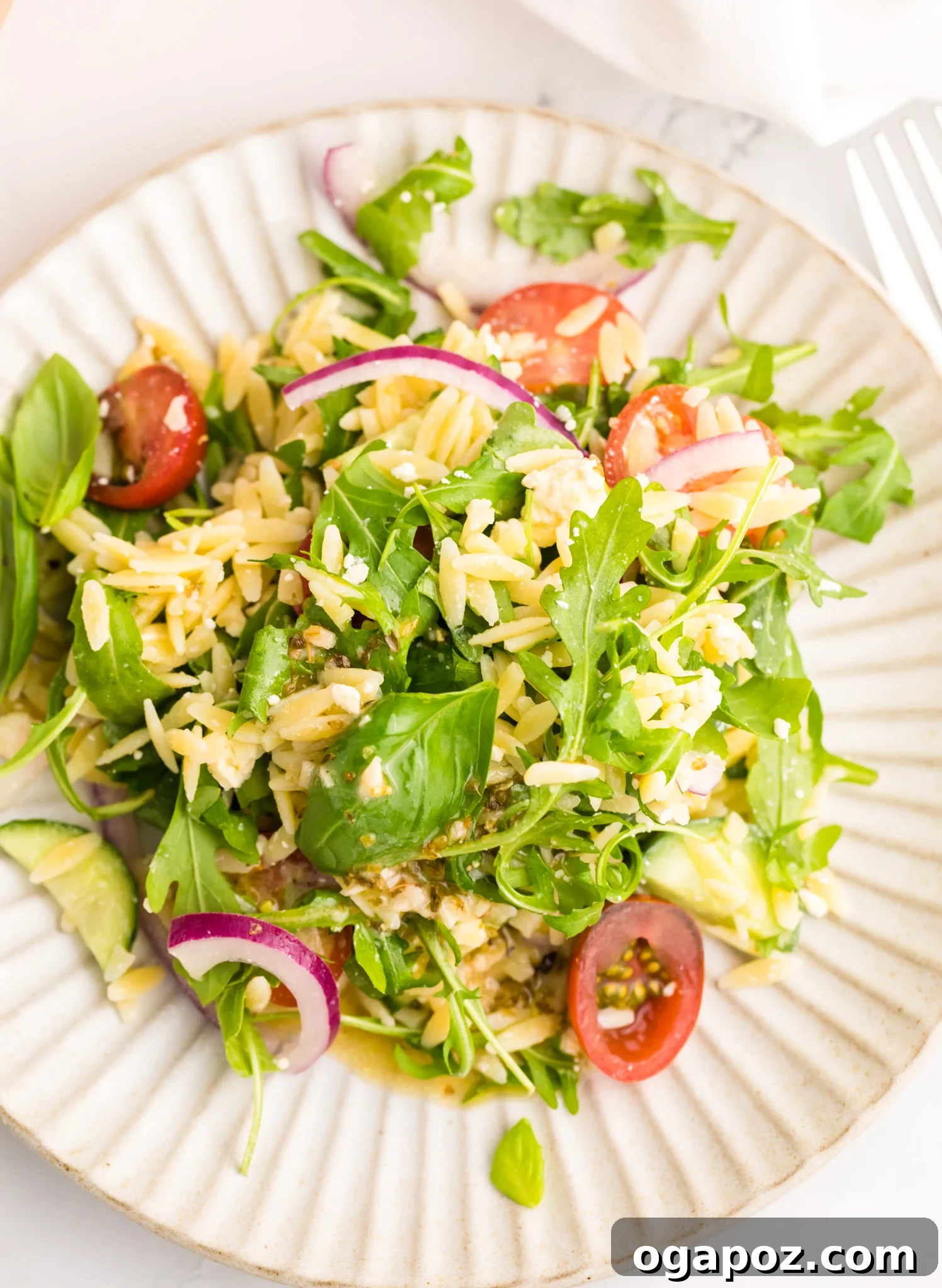 Vibrant Arugula Orzo Salad 7 A single serving of Arugula Orzo Salad on a white plate, ready to be eaten.