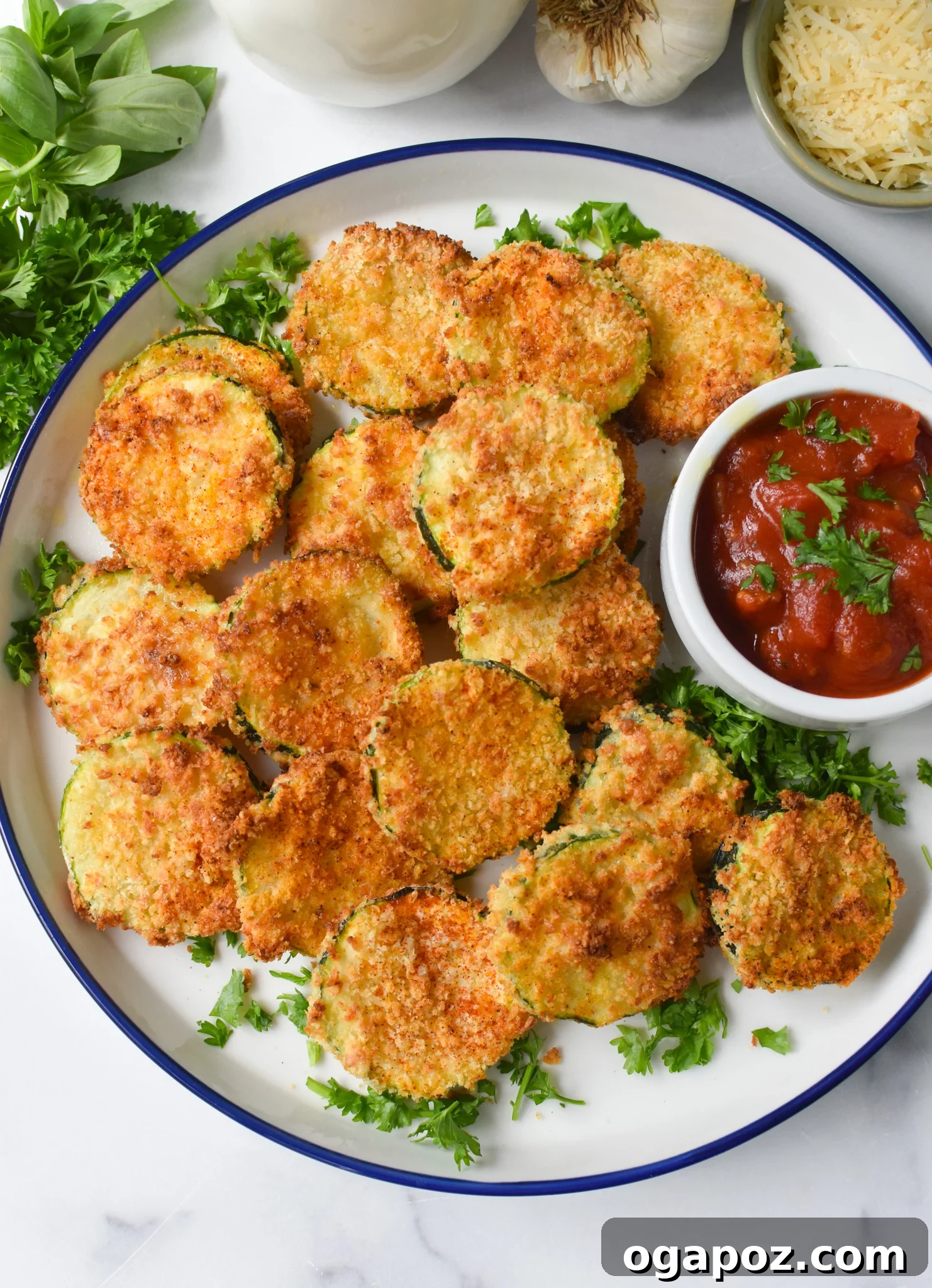 Crispy Air Fryer Zucchini Crisps 2 Air Fryer Zucchini Chips on a white plate, garnished with fresh herbs.