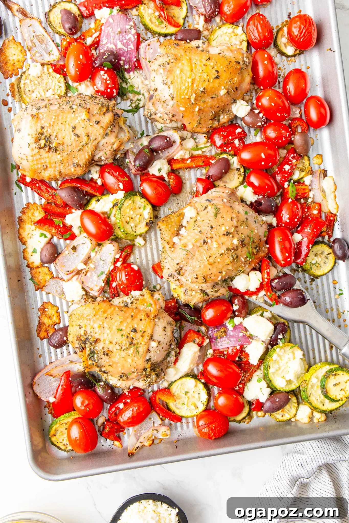 Zesty Mediterranean Sheet Pan Chicken 6 Mediterranean Sheet Pan Chicken served with a spoon, highlighting the juicy chicken and roasted vegetables.