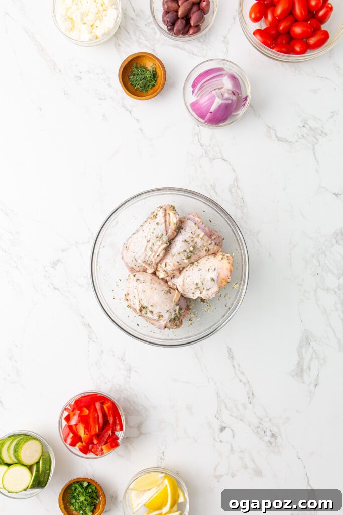 Zesty Mediterranean Sheet Pan Chicken 7 Chicken thighs marinating in a bowl with Mediterranean herbs and lemon.