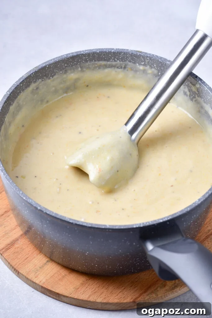Velvety Potato Leek Soup 9 A cook using a handheld immersion blender to puree Potato Leek Soup in a pot.