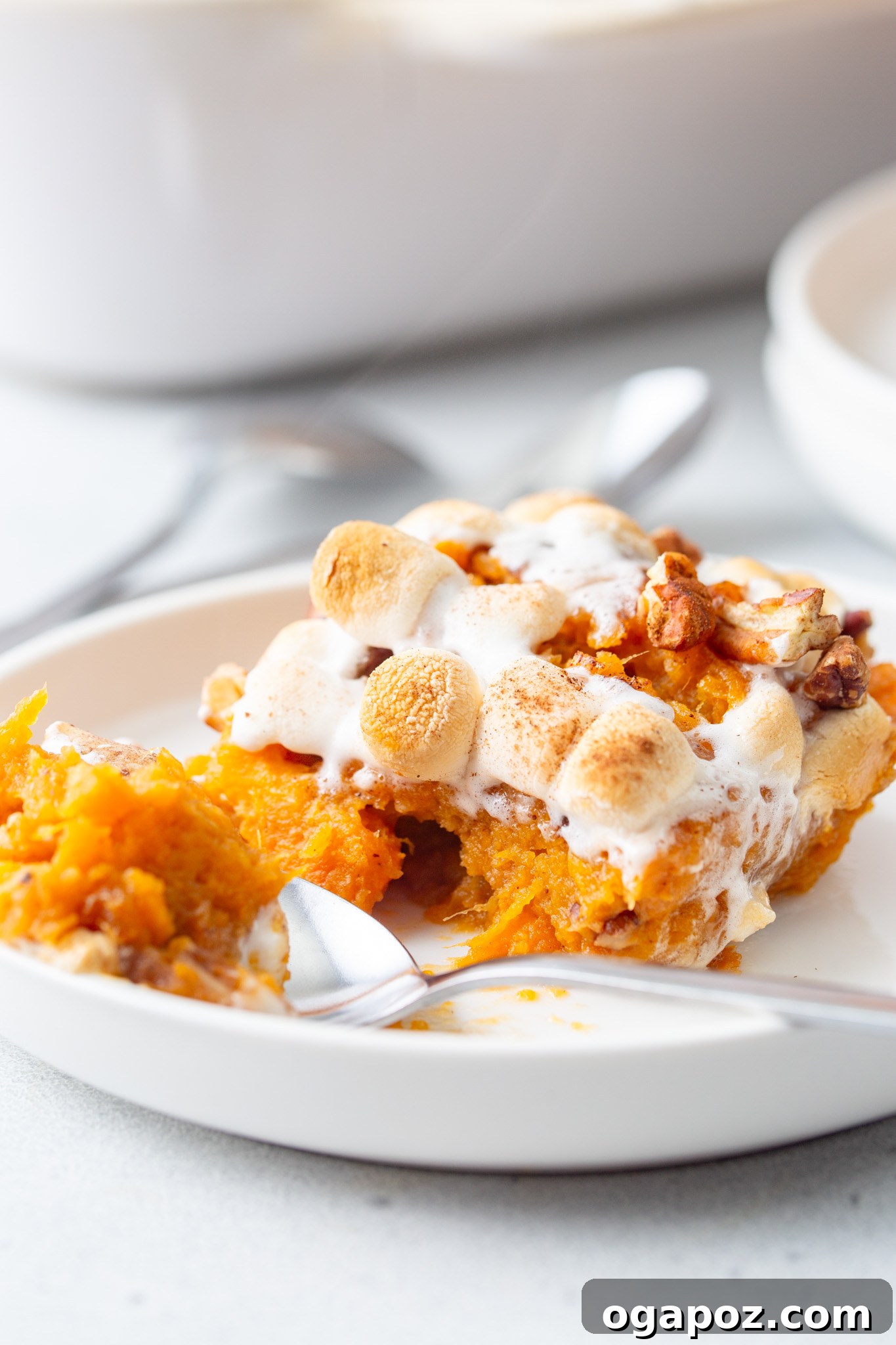 Golden Sweet Potato Marshmallow Delight 3 Sweet Potato Casserole with Marshmallows being scooped with a spoon, showing its creamy texture and gooey topping