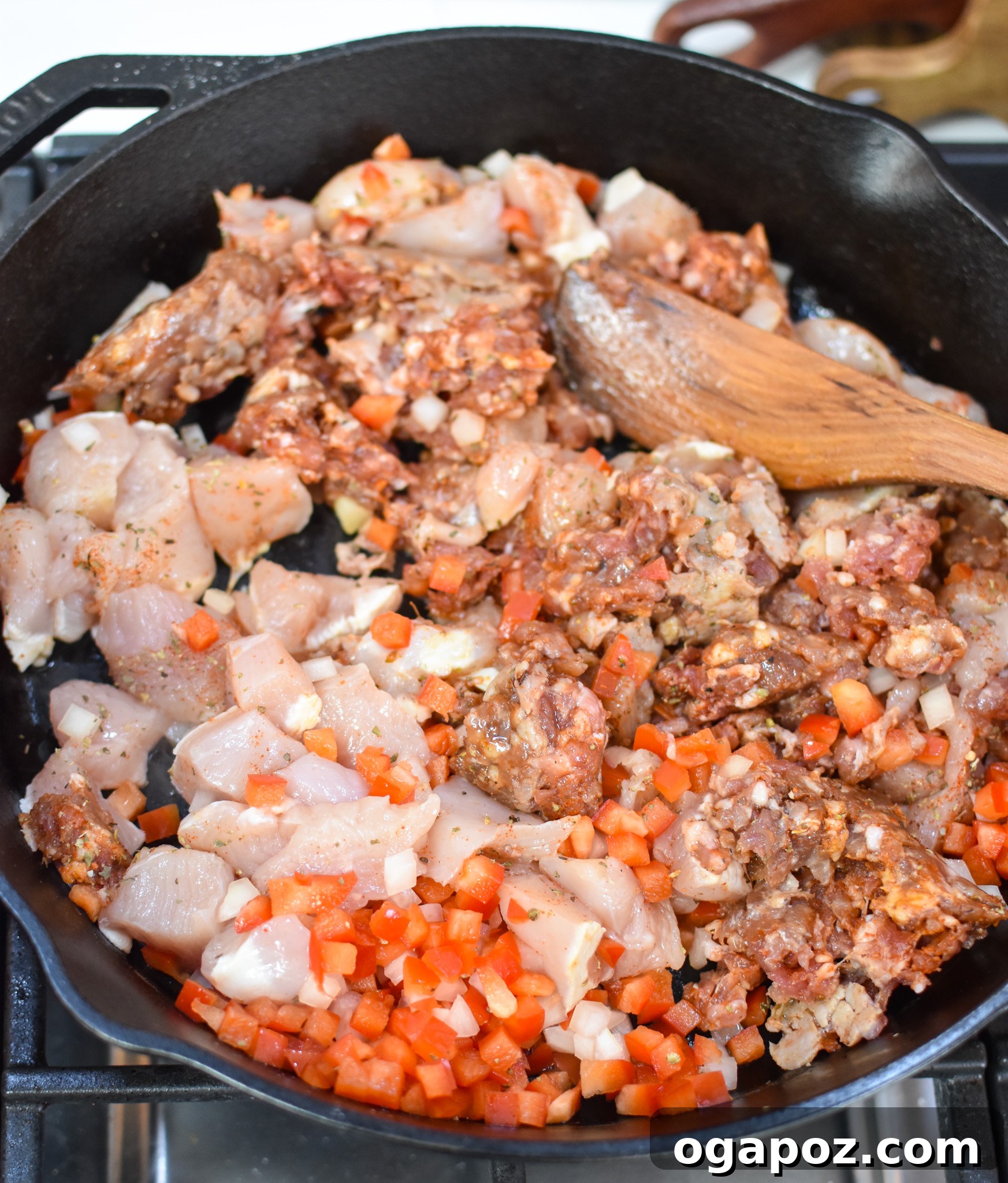 Irresistible Creamy Chicken Chorizo Pasta 6 Adding diced tomatoes to the chicken and chorizo mixture in a cast iron skillet.