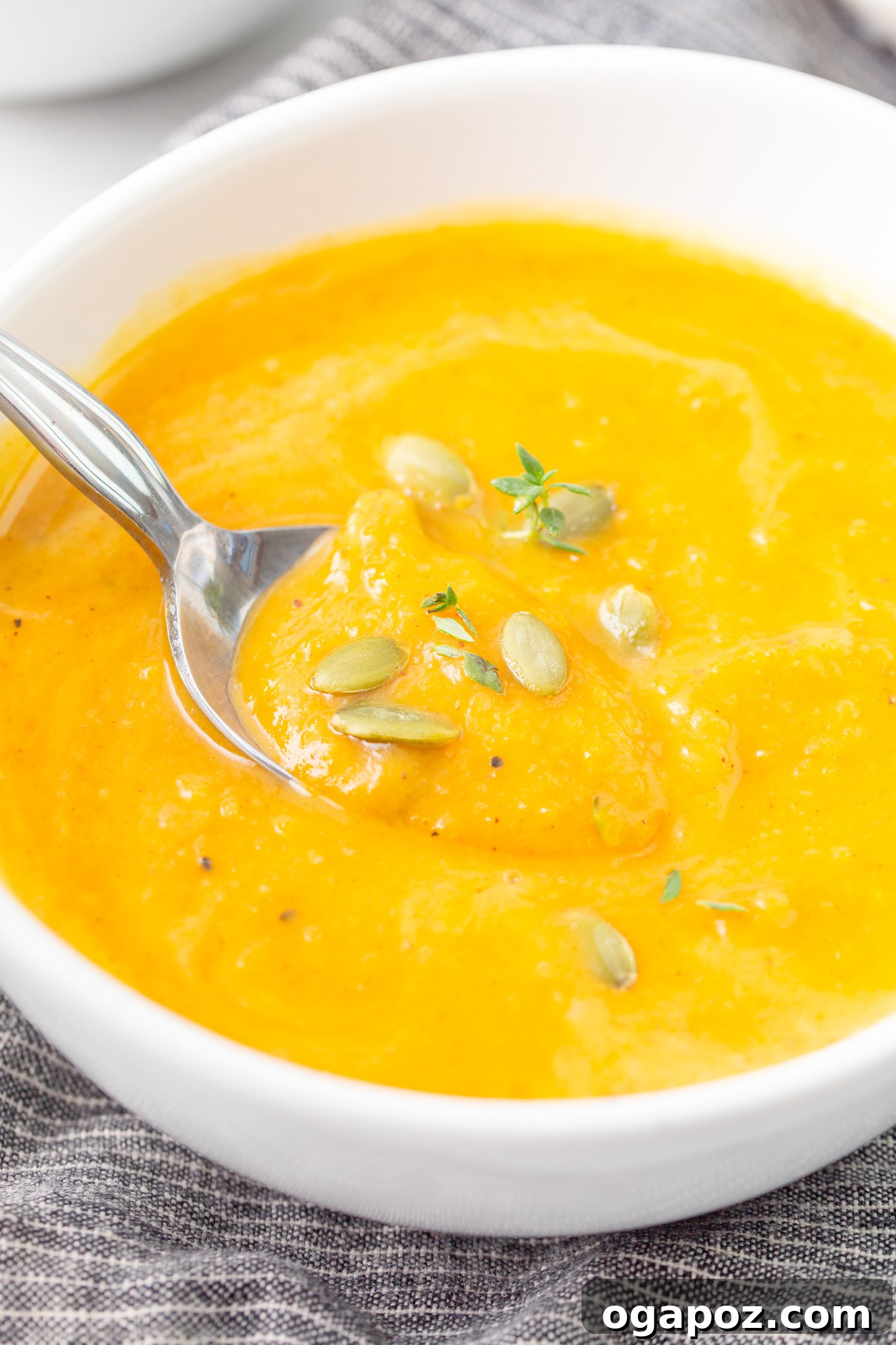 Creamy Roasted Butternut Squash Soup 2 A steaming bowl of Easy Roasted Butternut Squash Soup with a spoon resting in it, garnished with fresh herbs.
