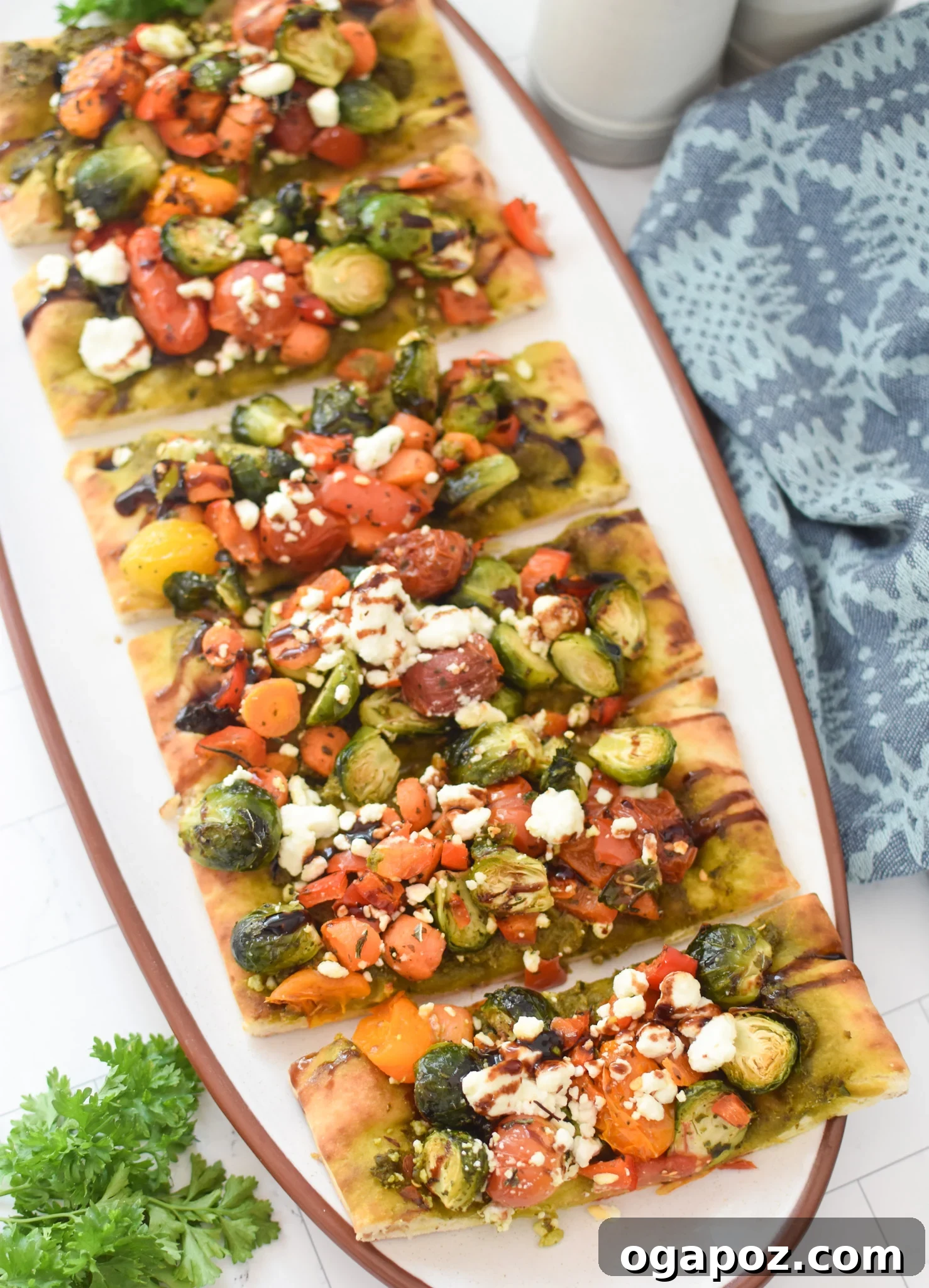 Gourmet Goat Cheese and Roasted Vegetable Flatbread 12 A freshly baked Roasted Vegetable Goat Cheese Flatbread Pizza, sliced and garnished with fresh herbs, on a cutting board.