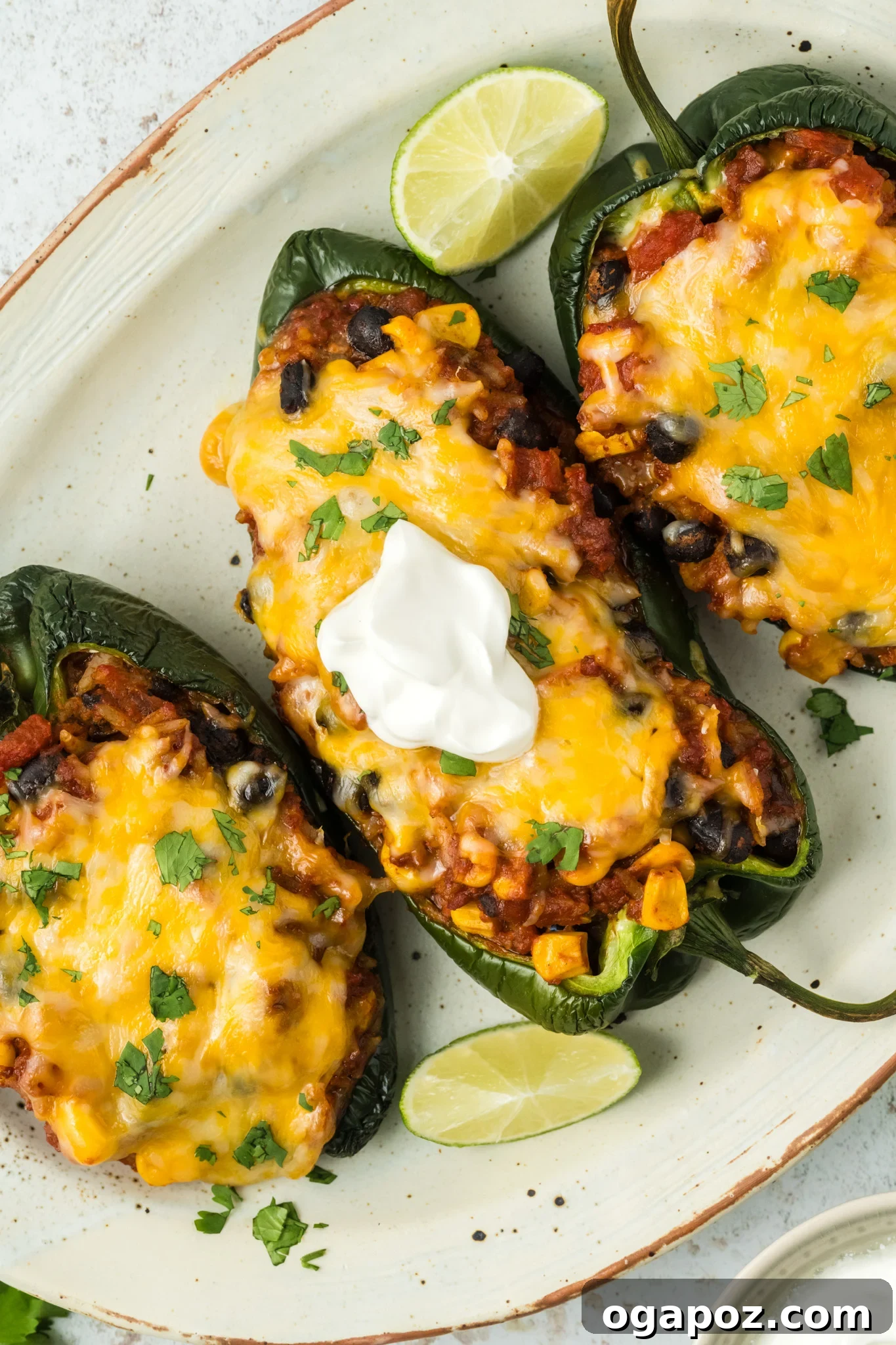 Cheesy Stuffed Poblano Peppers 2 Delicious Stuffed Poblano Peppers served on a platter, garnished with sour cream and fresh herbs.