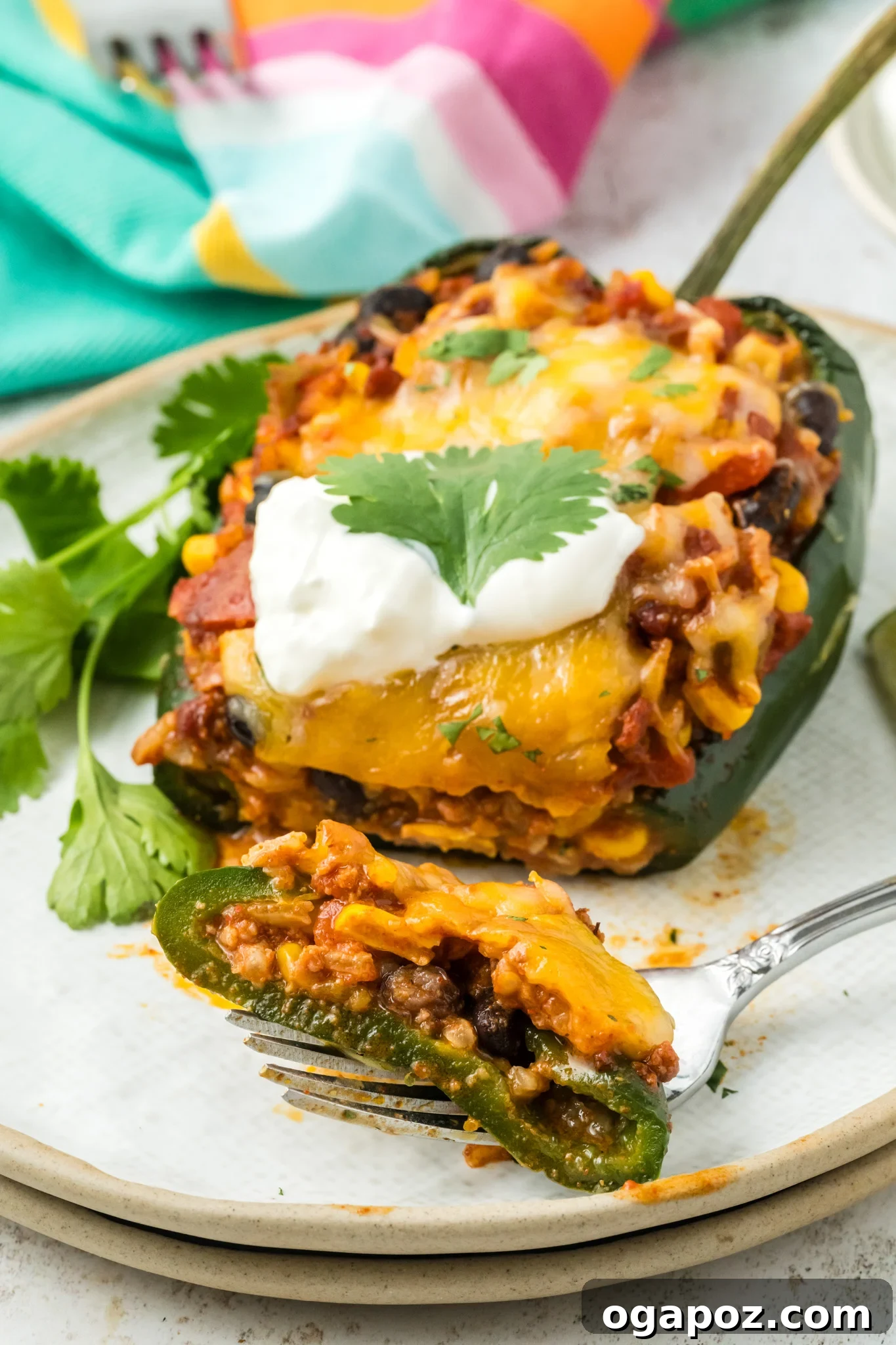 Cheesy Stuffed Poblano Peppers 4 A single stuffed poblano pepper on a plate with a fork, showing the rich, savory filling and melted cheese.