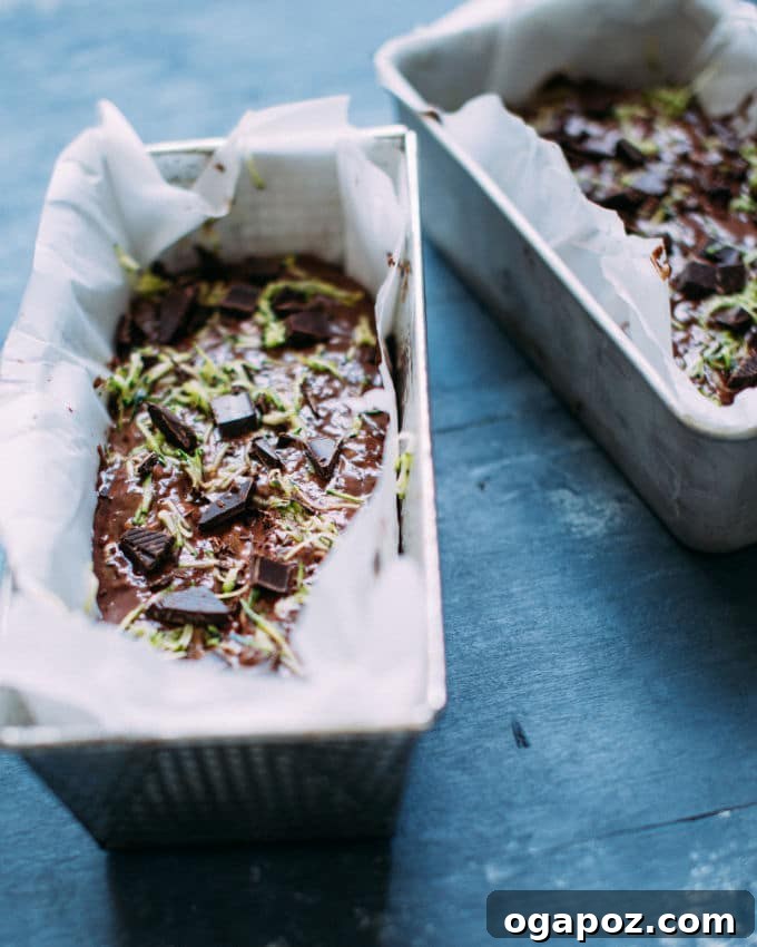 Hidden Veggie Chocolate Bread 4 A single slice of chocolate zucchini bread on a white plate, showcasing its fluffy, moist interior with visible chocolate chunks and flecks of zucchini.