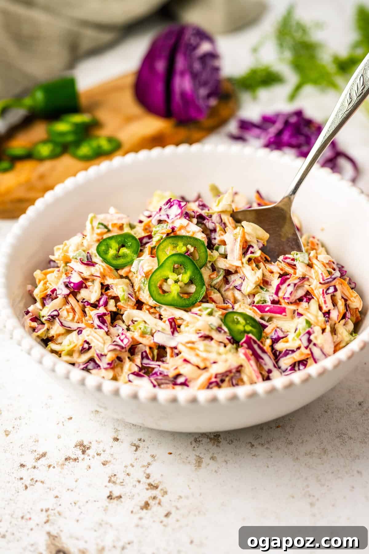 Kickin' Creamy Jalapeno Coleslaw 2 Fresh Jalapeno Coleslaw Recipe in a white bowl with a fork, ready to be served as a vibrant side dish.