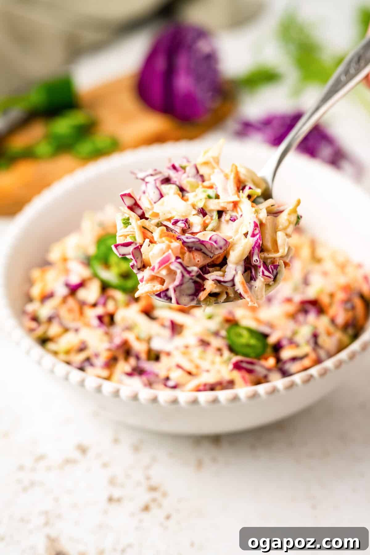 Kickin' Creamy Jalapeno Coleslaw 7 A serving of spicy Jalapeno Coleslaw in a white bowl, with a fork resting inside, ready to be enjoyed.