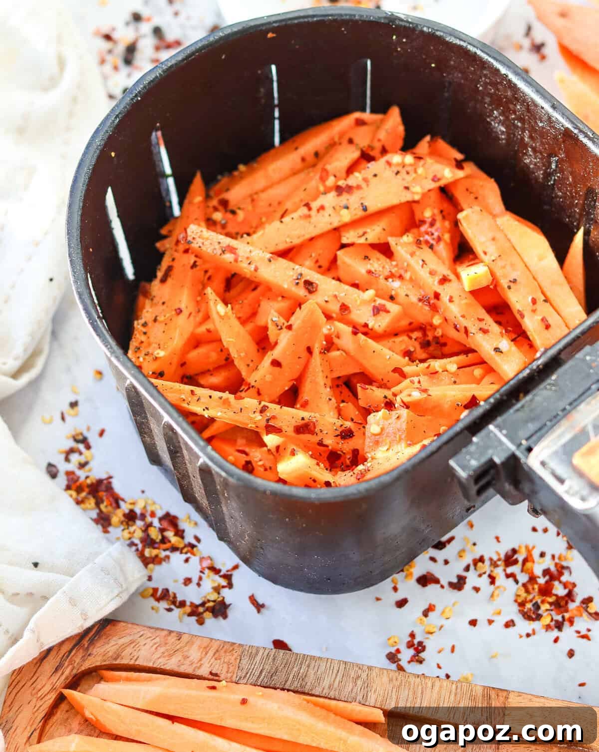 Crispy Air-Fried Sweet Potato Fries 3 Raw sweet potato fries tossed with seasoning in an air fryer basket, ready to cook.