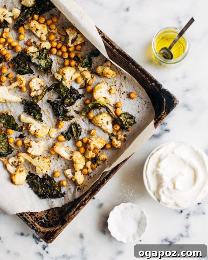 Golden Roasted Cauliflower, Kale & Crispy Chickpea Salad 4 A close-up of crispy roasted chickpeas and perfectly cooked vegetables on a baking sheet.