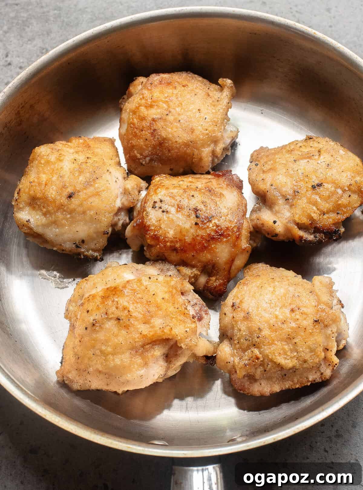 Sticky Honey Ginger Chicken 8 Chicken thighs searing in a hot skillet until golden brown.