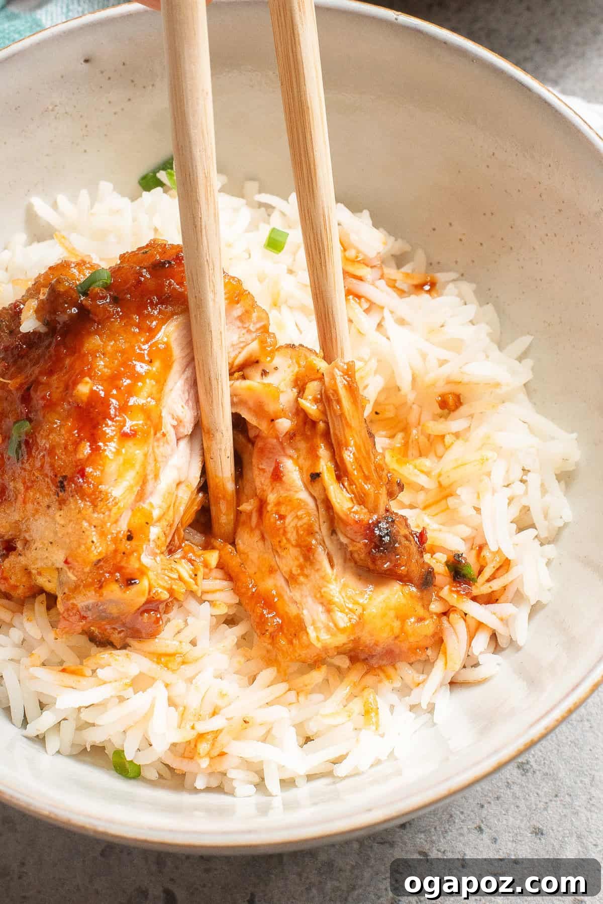 Sticky Honey Ginger Chicken 10 Honey Ginger Chicken served in a bowl, being picked up with chopsticks.