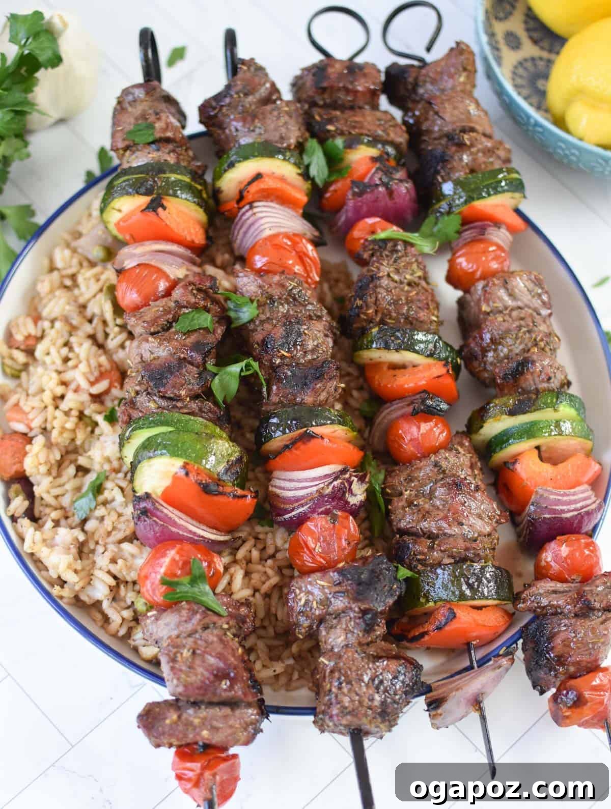 Grilled Beef Souvlaki Skewers 3 Beef Souvlaki served over a bowl of fluffy rice, garnished with fresh herbs.