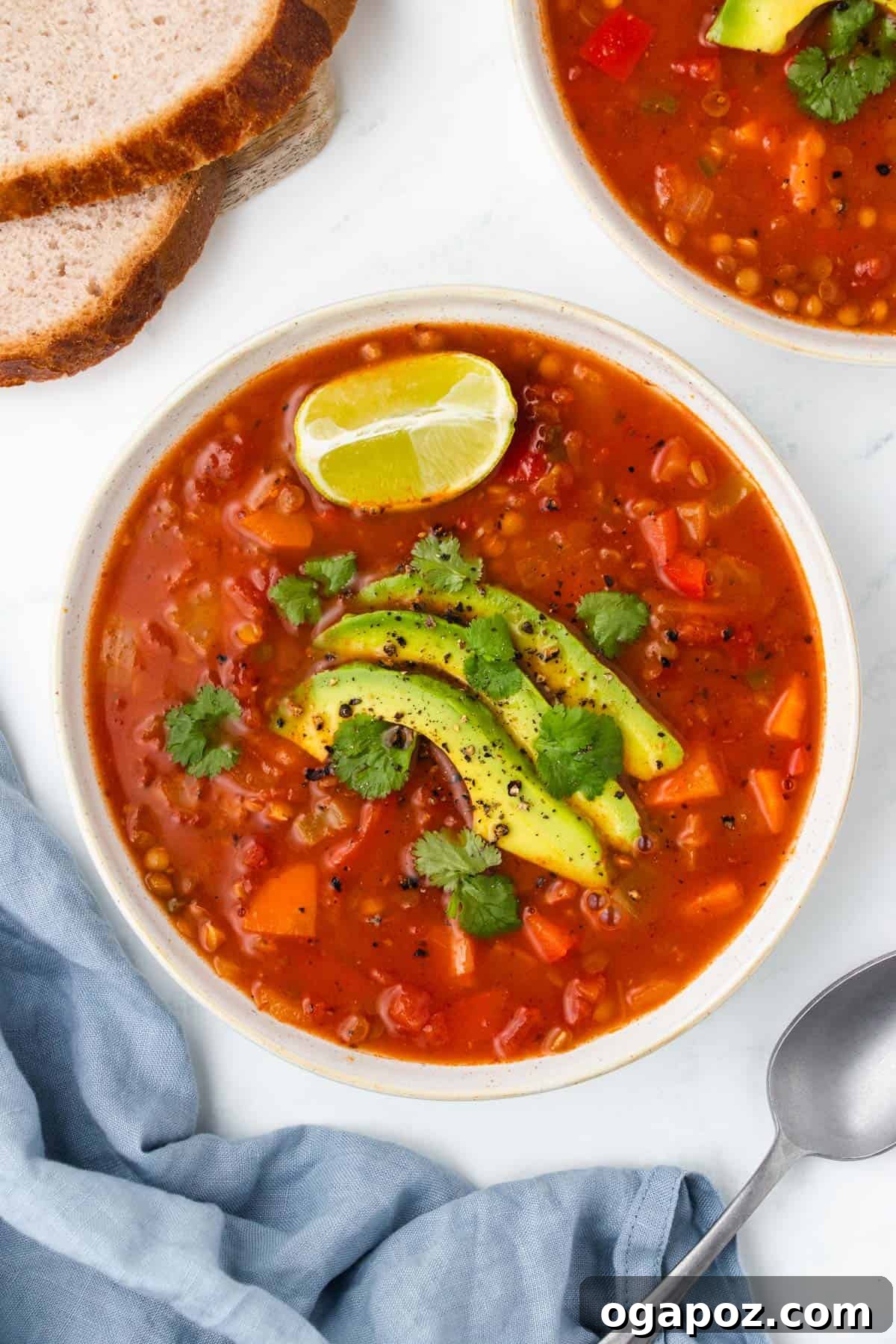 Flavorful Mexican Lentil Stew 2 Mexican Lentil Soup with avocado and lime wedges on a wooden board.