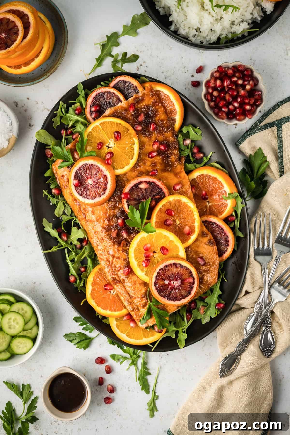 Zesty Orange Glazed Salmon 6 Perfectly cooked Orange Glazed Salmon on a black plate, garnished with pomegranate seeds and fresh herbs.