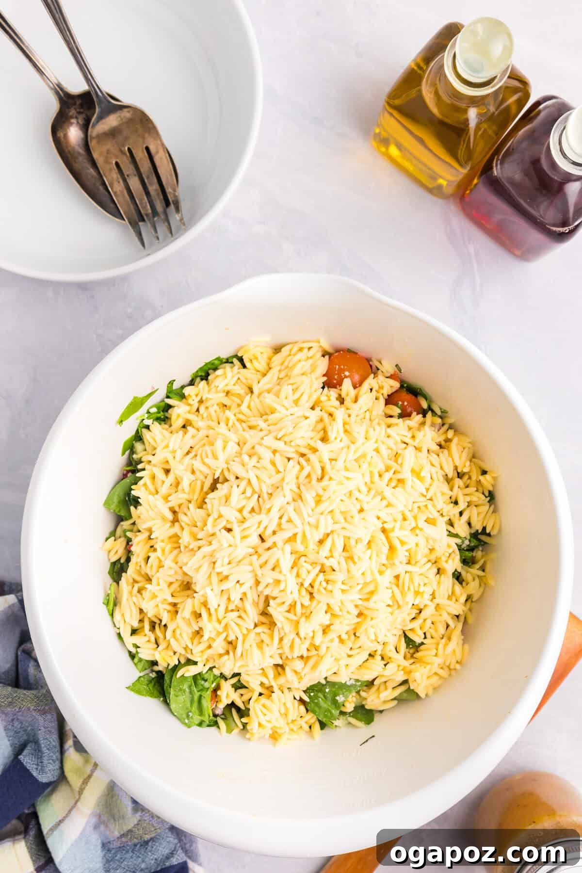 Mediterranean Garden Pasta 9 Cooled orzo pasta being added into a large mixing bowl, joining the vibrant medley of Mediterranean salad ingredients.
